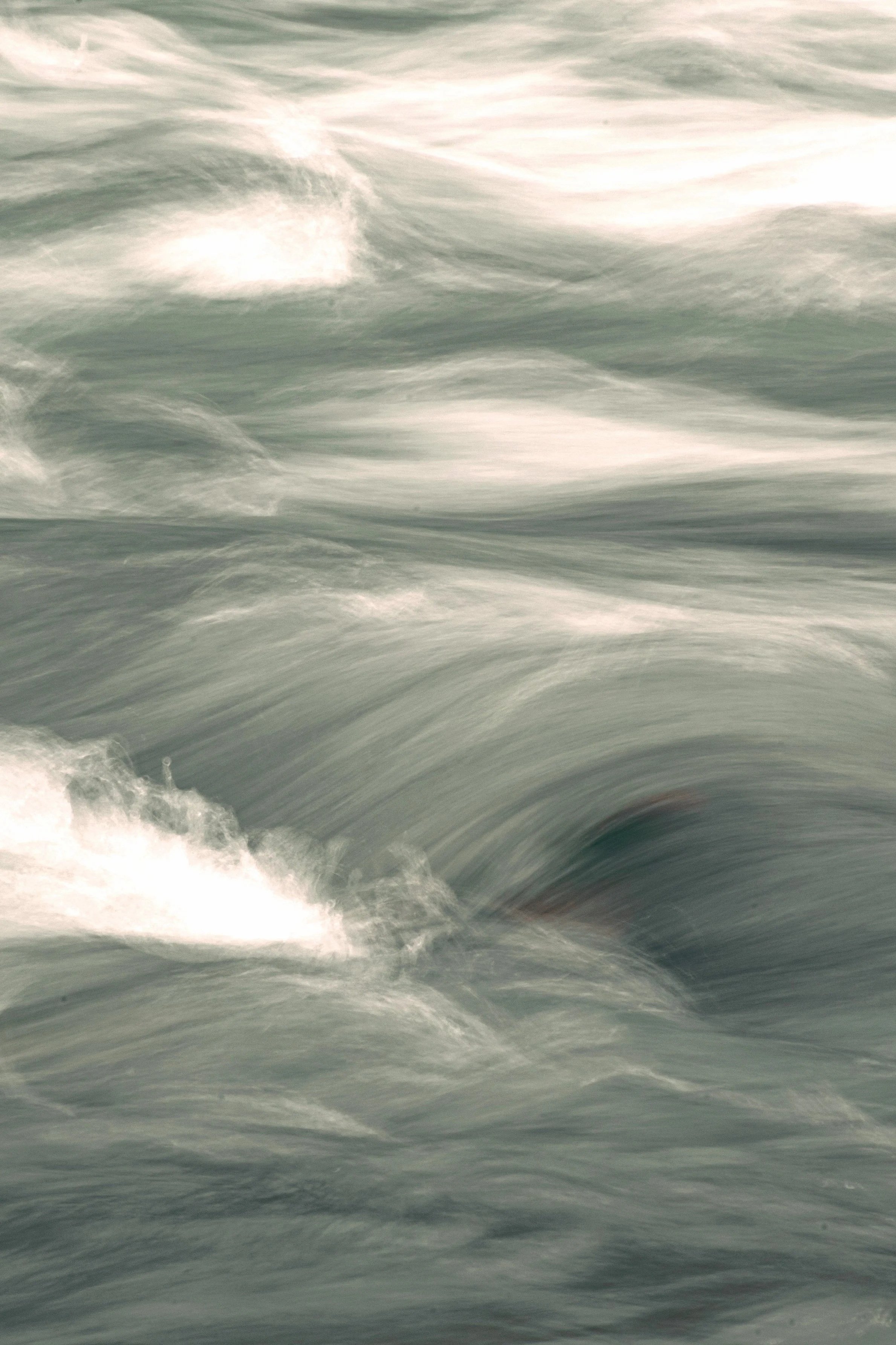 De afbeelding toont de beweging van stromend water of golven in de zee of oceaan, met wit schuimende golven en een groene tot blauwe kleur van het water.