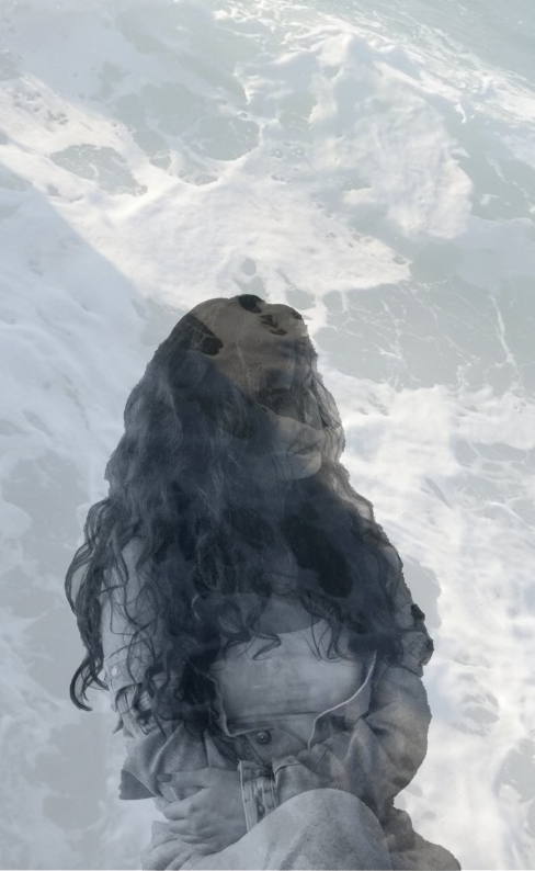 Een dubbelgelaagde afbeelding van een vrouw met lang, krullend haar die op het strand zit, met de oceaan en opkomende golven op de achtergrond.
