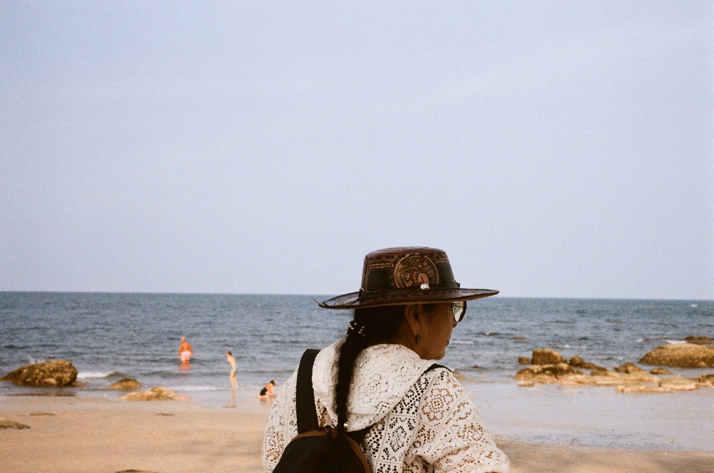 A person wearing a wide-brimmed sun hat looking out at the ocean on Hua Hin beach.
