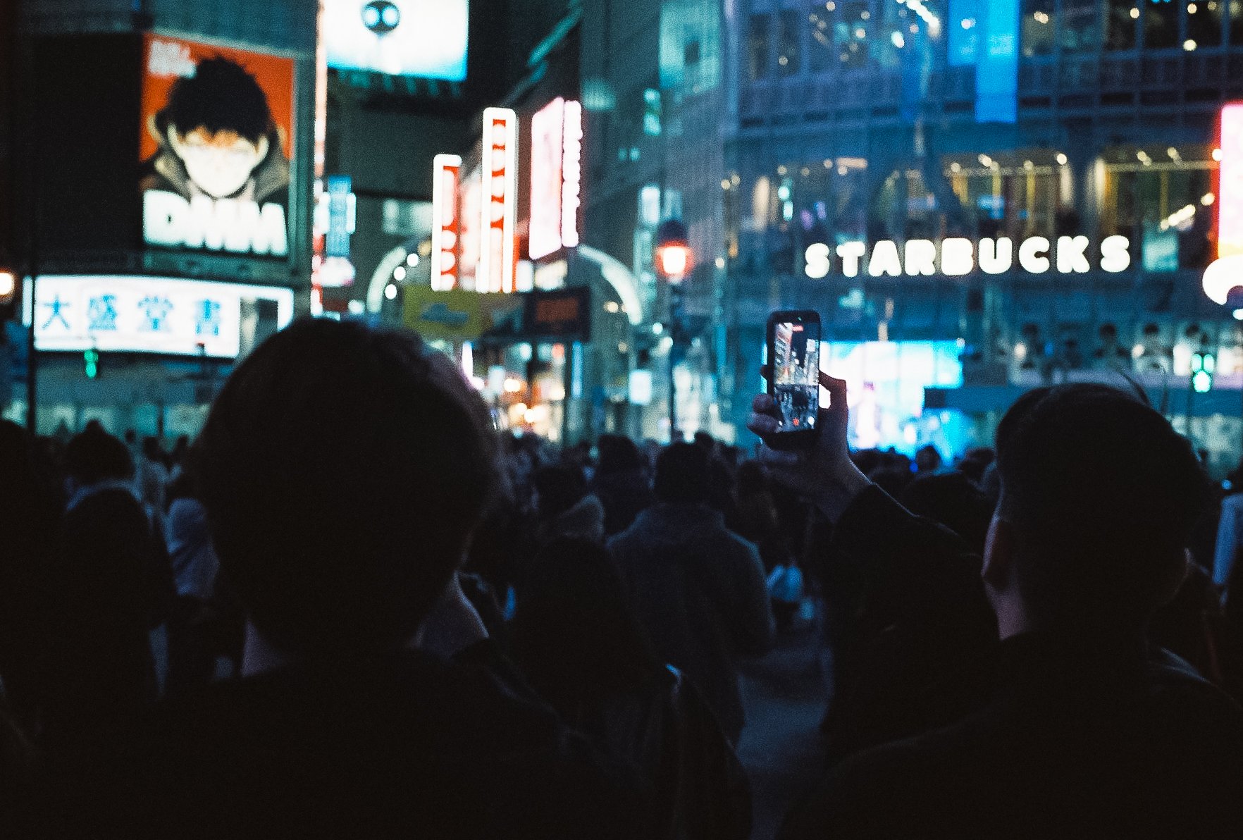 Large crowd of people gathered at a brightly lit Tokyo street crossing, cinematic night photography.