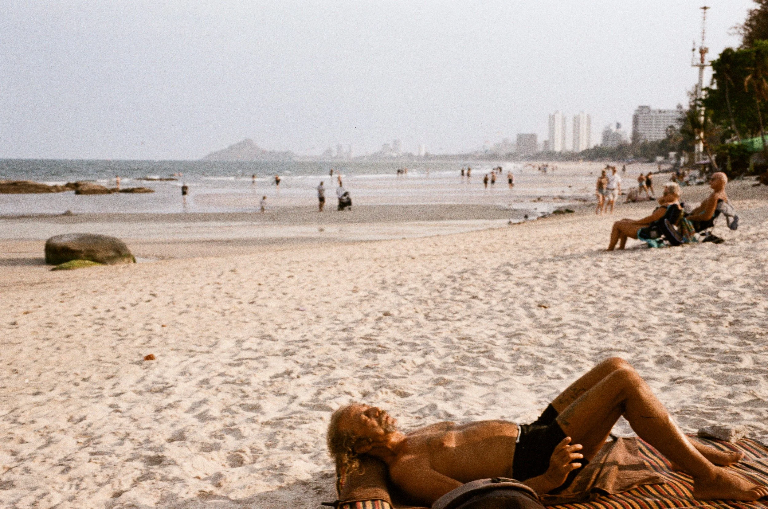 A sunbather relaxing on the sandy beach of Hua Hin, Thailand, taken on Leica film.