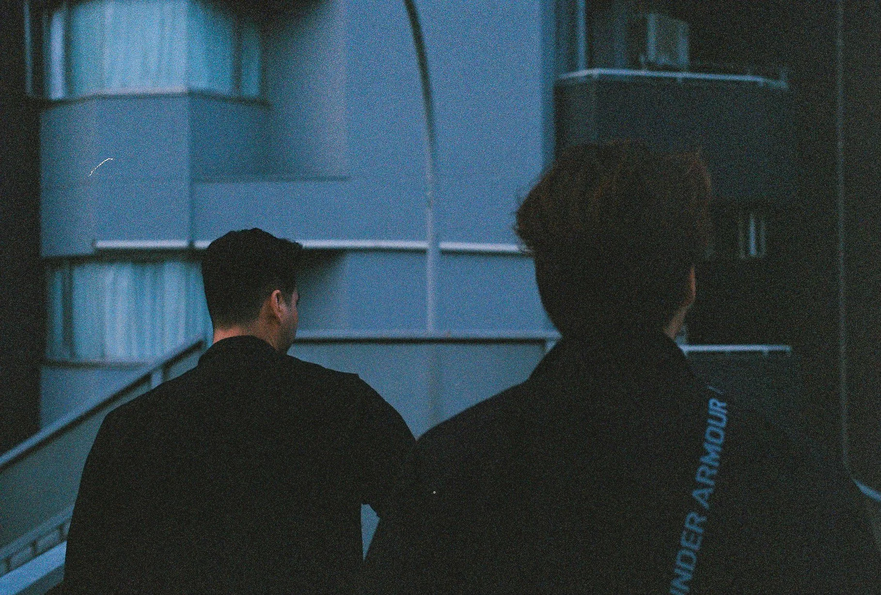 Cinematic street photography of two silhouetted figures walking at dusk with cool blue tones.