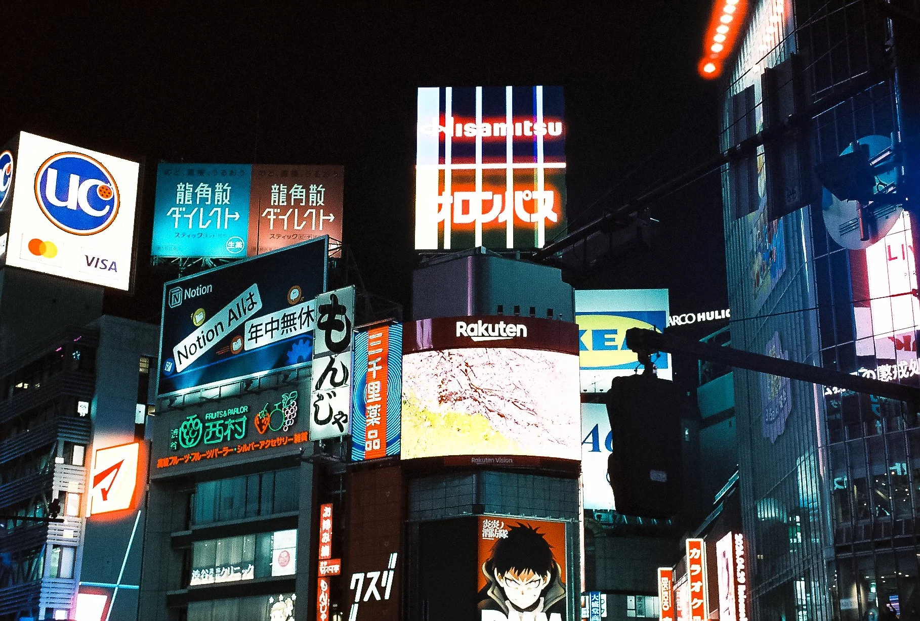 Glowing neon building facades and illuminated Japanese street signs at night in Tokyo.