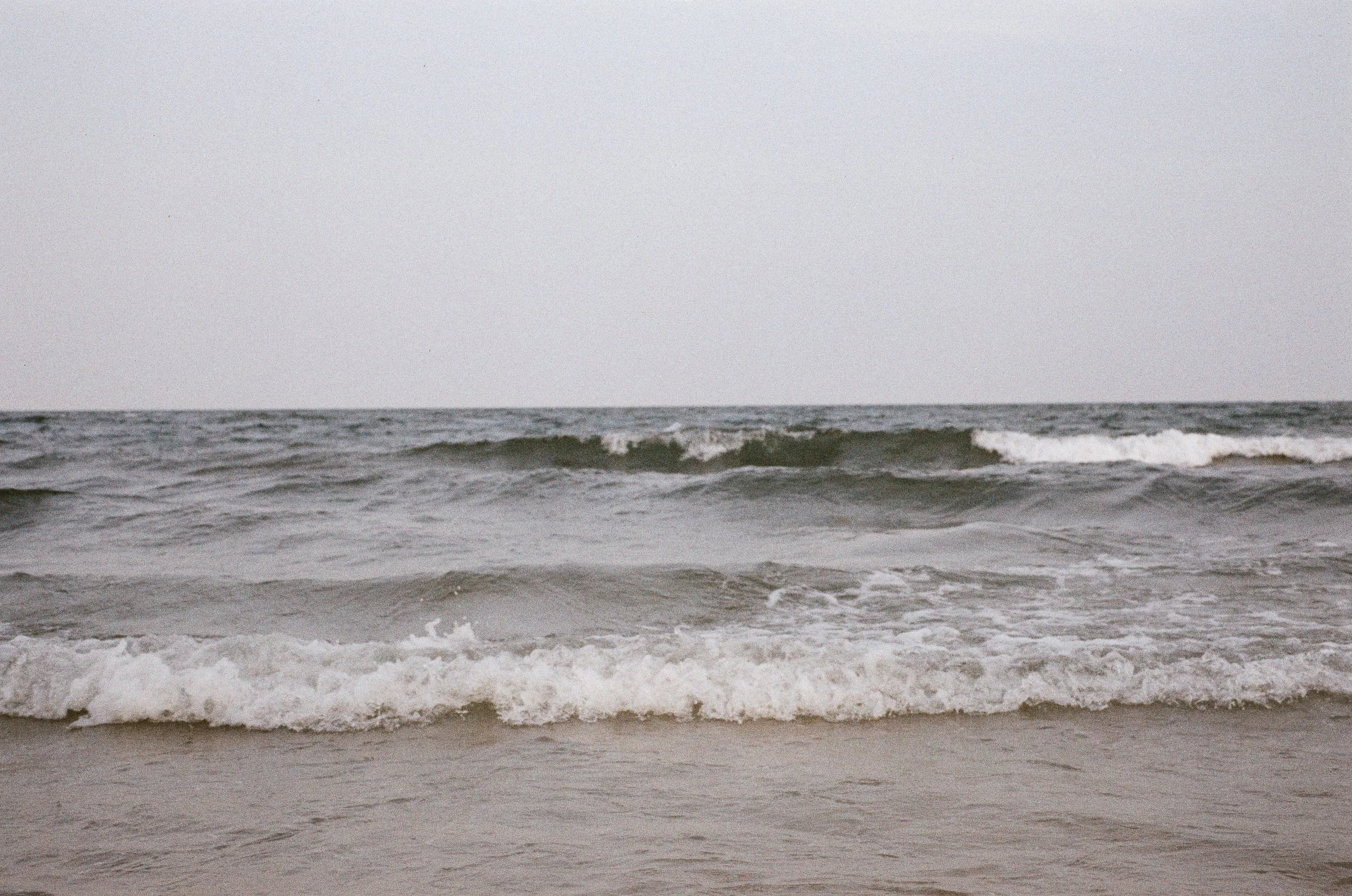 A moody landscape of deep ocean waves breaking on a quiet beach in Thailand.