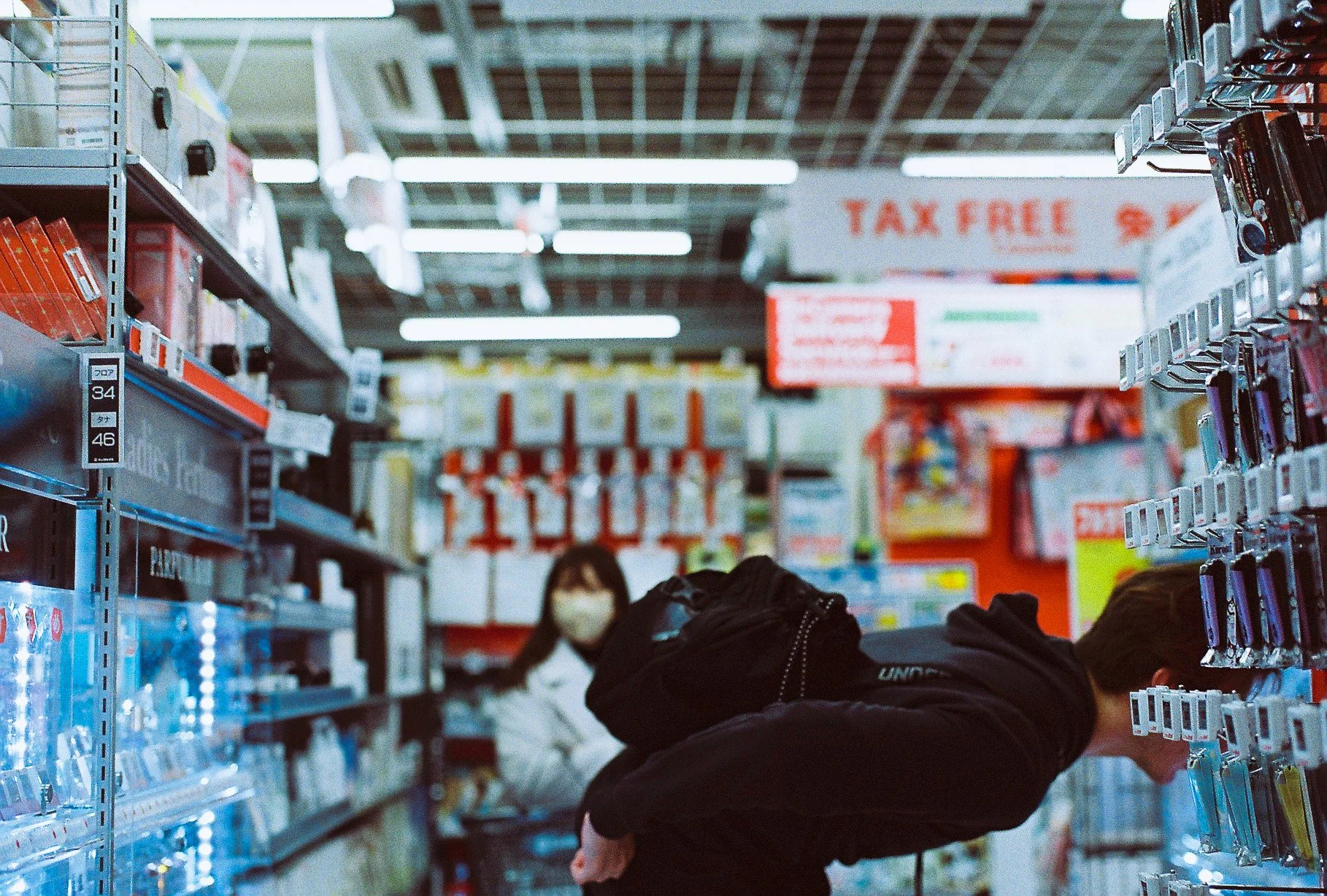 POV shot shopping down an aisle inside a brightly lit Japanese tax-free store in Tokyo.