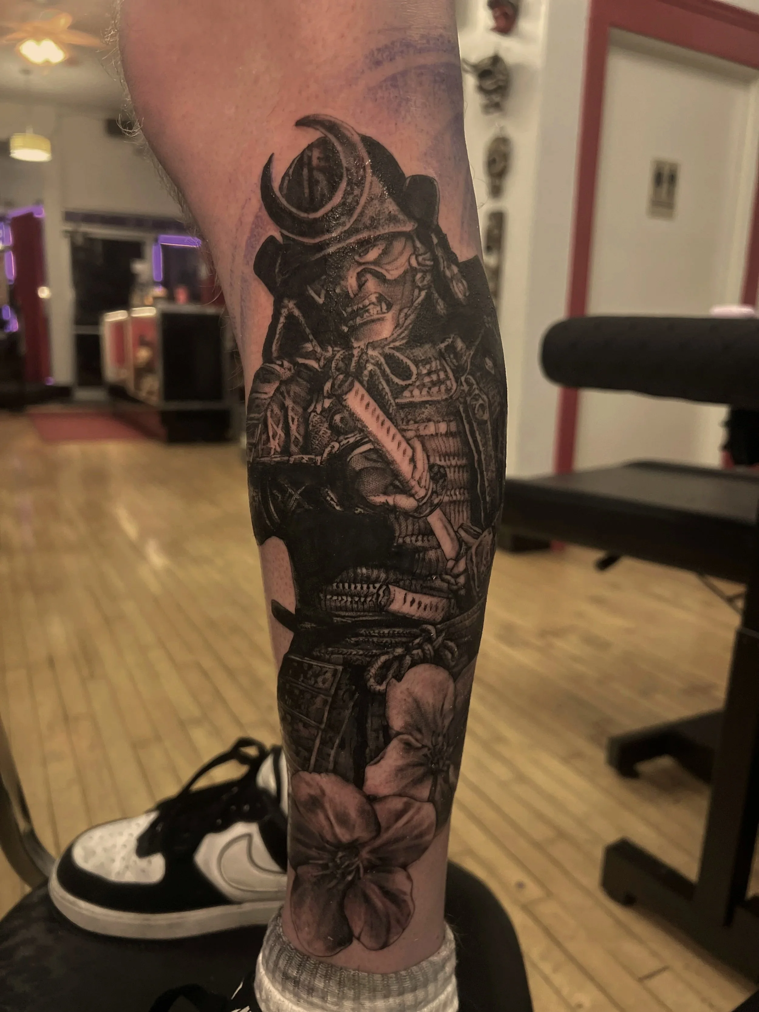 Tattoo of a Viking warrior with a horned helmet, chainmail, and axe on person's arm.