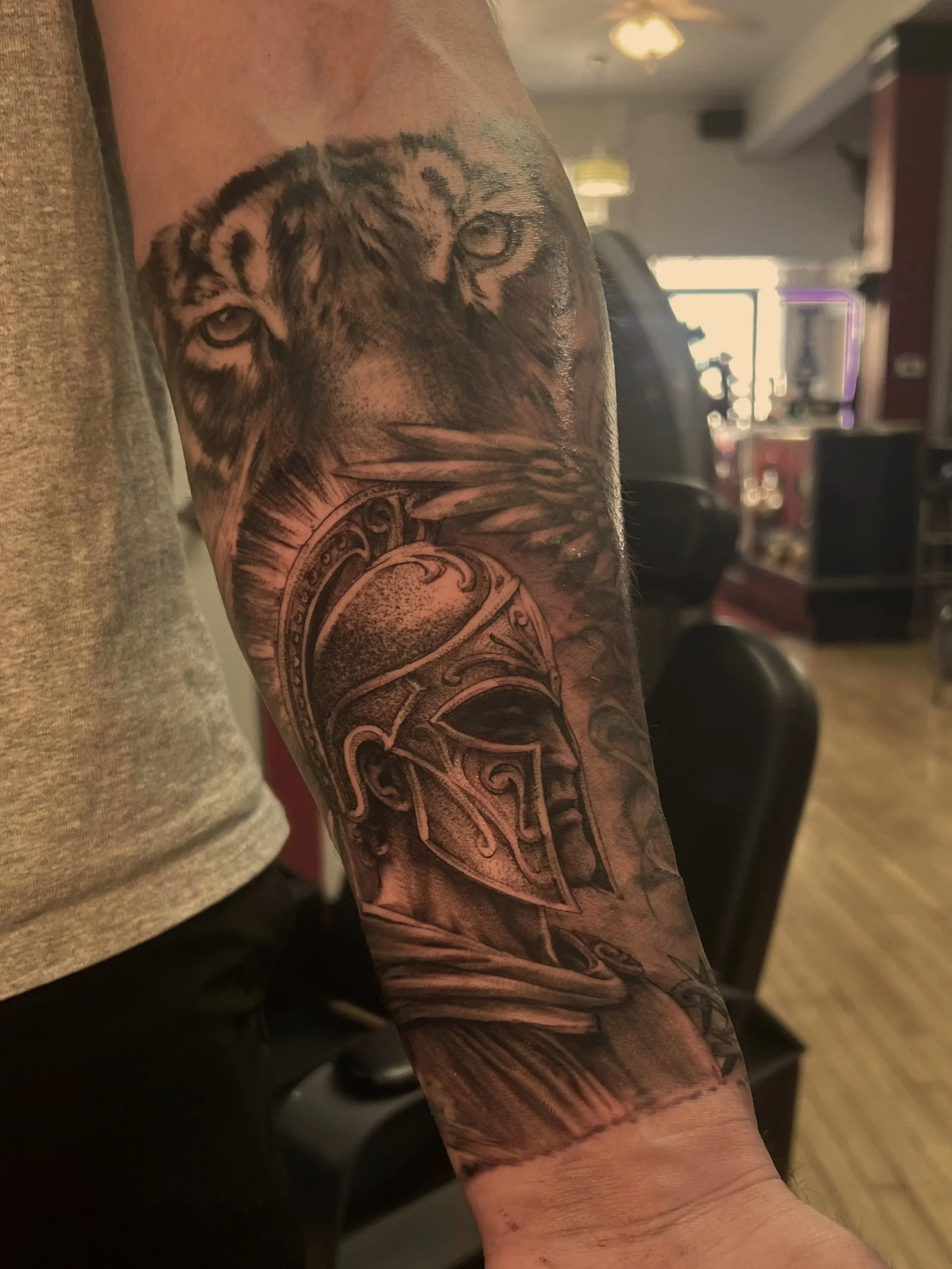 Close-up of a person's arm with a tattoo of a wolf's face, showing detailed shading and design.