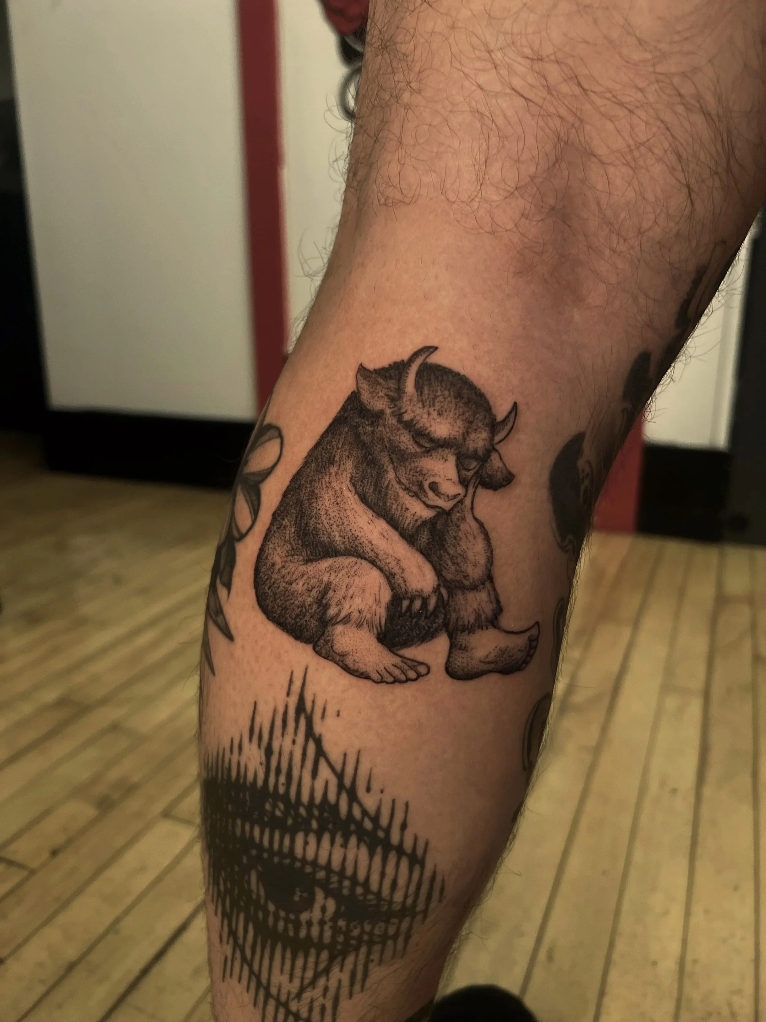 Tattoo of a lion curled up on the person's arm. Reference from Where the Wild Things are tattoo.