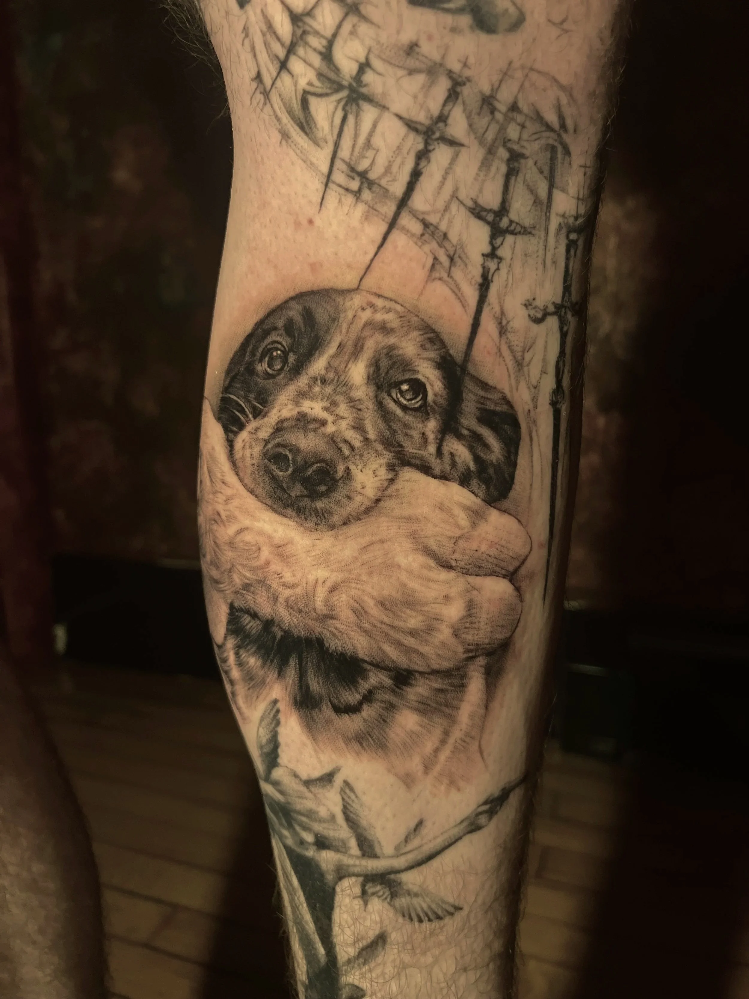 Tattoo of a puppy dog’s face with a black and white floral background.