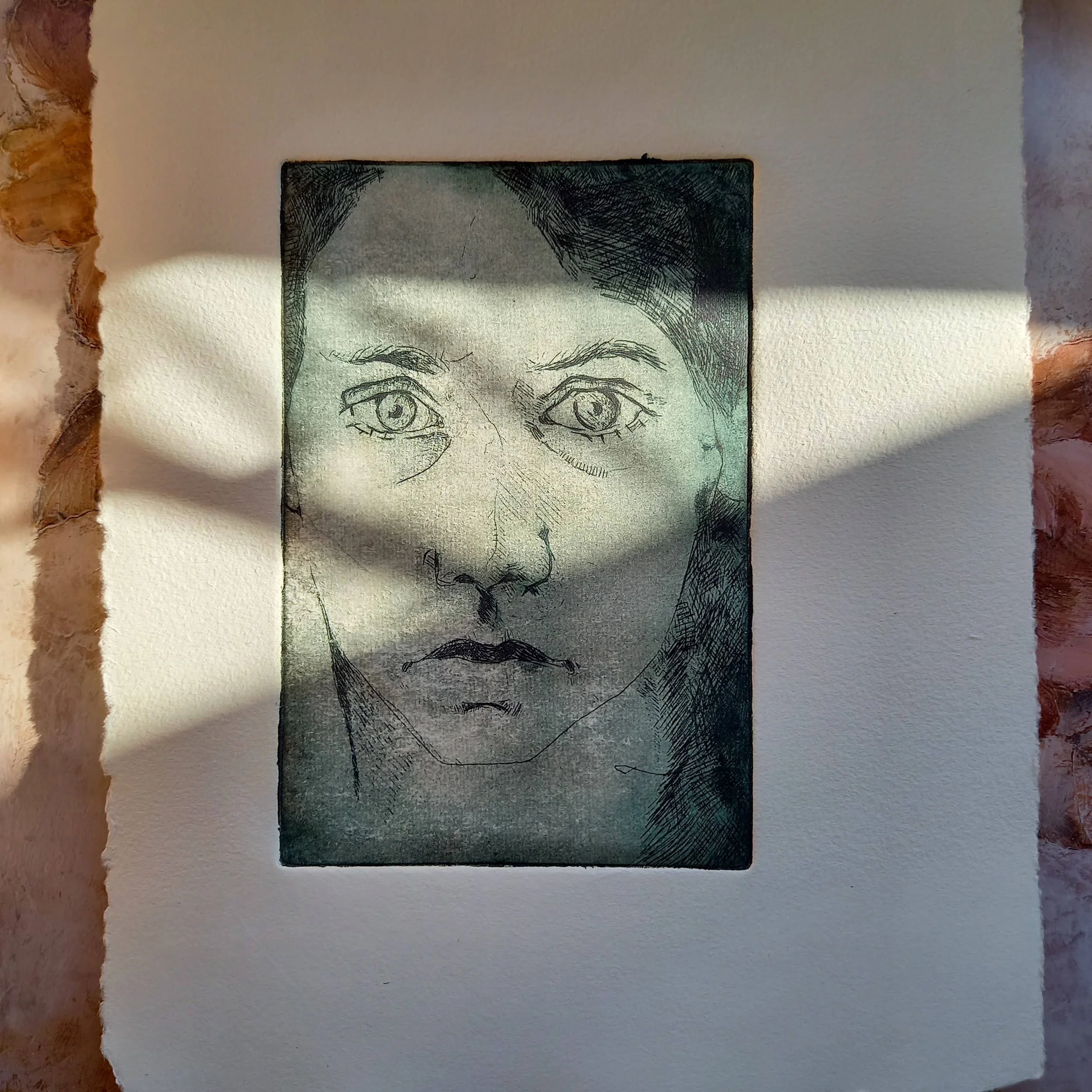 Drawing of a woman's face with detailed eyes and eyebrows on a piece of paper, placed on a white and brown textured background.