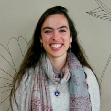 Cass Baca, the MDT support coordinator for the Colorado Children's Alliance, is a young woman with long dark hair wearing a light sweater, and patterned scarf.