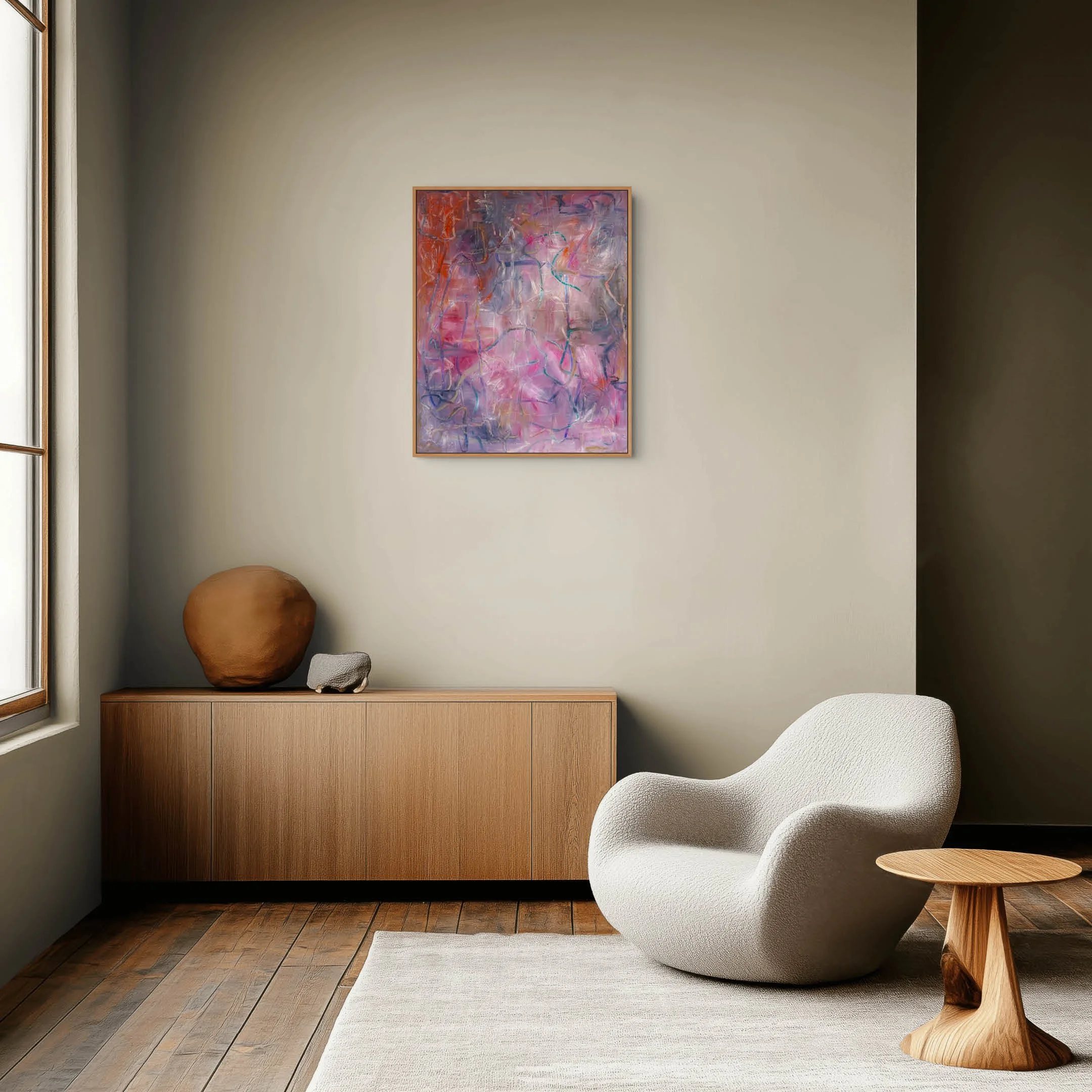 Modern interior with a white contemporary chair and a wooden side table, a wooden cabinet topped with decorative objects, a large abstract pink and purple painting on a beige wall, natural light from a window, and a beige area rug on wooden flooring.