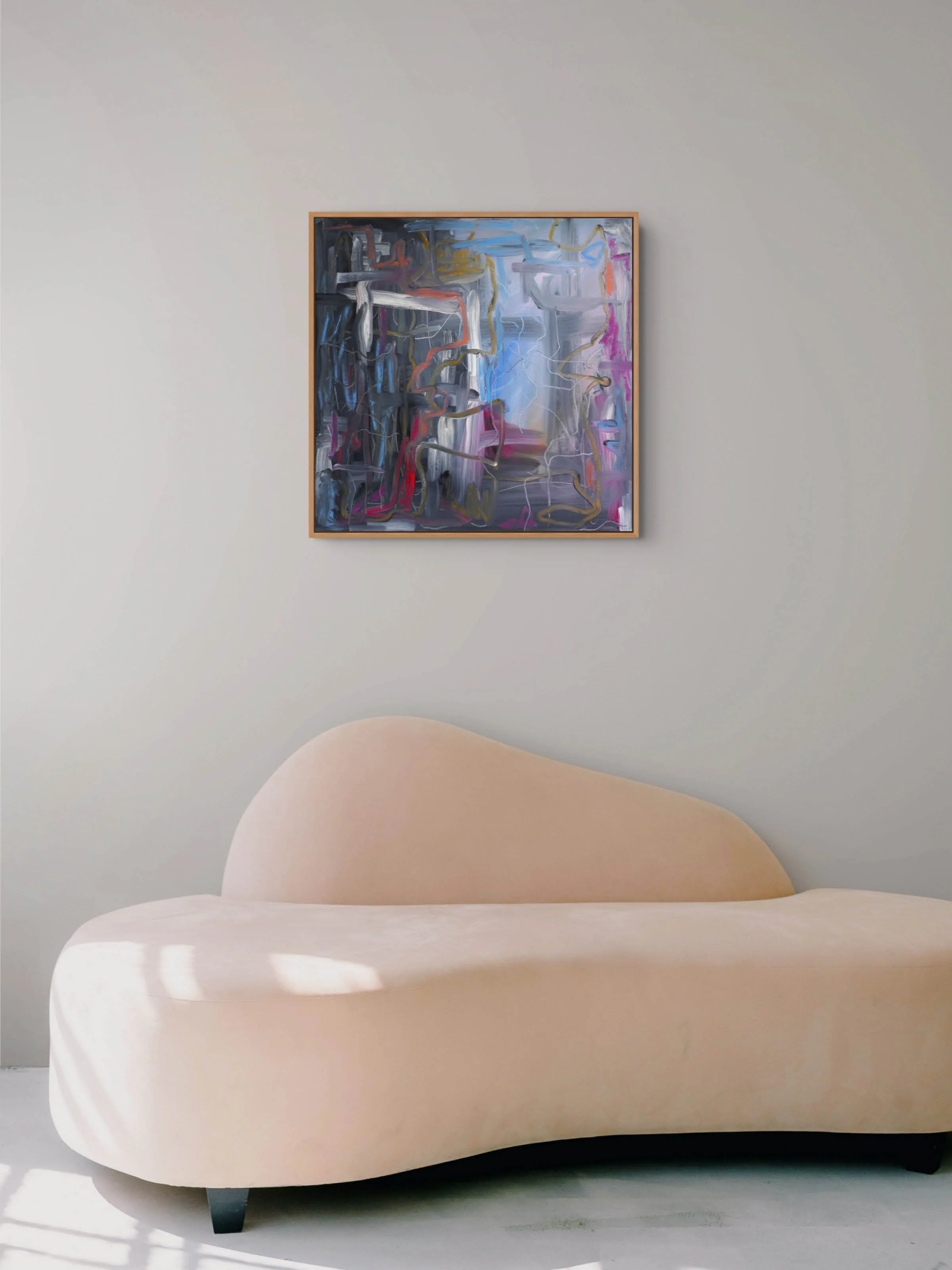 A modern, minimalistic beige armchair with rounded edges in front of a plain light grey wall. Hanging above the armchair is an abstract painting with various swirling colors including blue, pink, white, black, and purple.