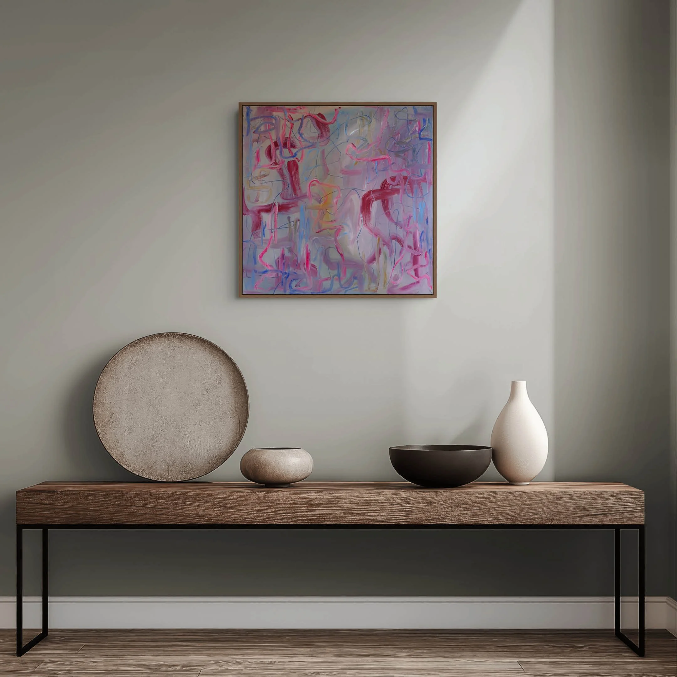 Modern interior with a black metal and wood table, decorative white vases, a textured beige plate, and an abstract colorful painting on a gray wall.
