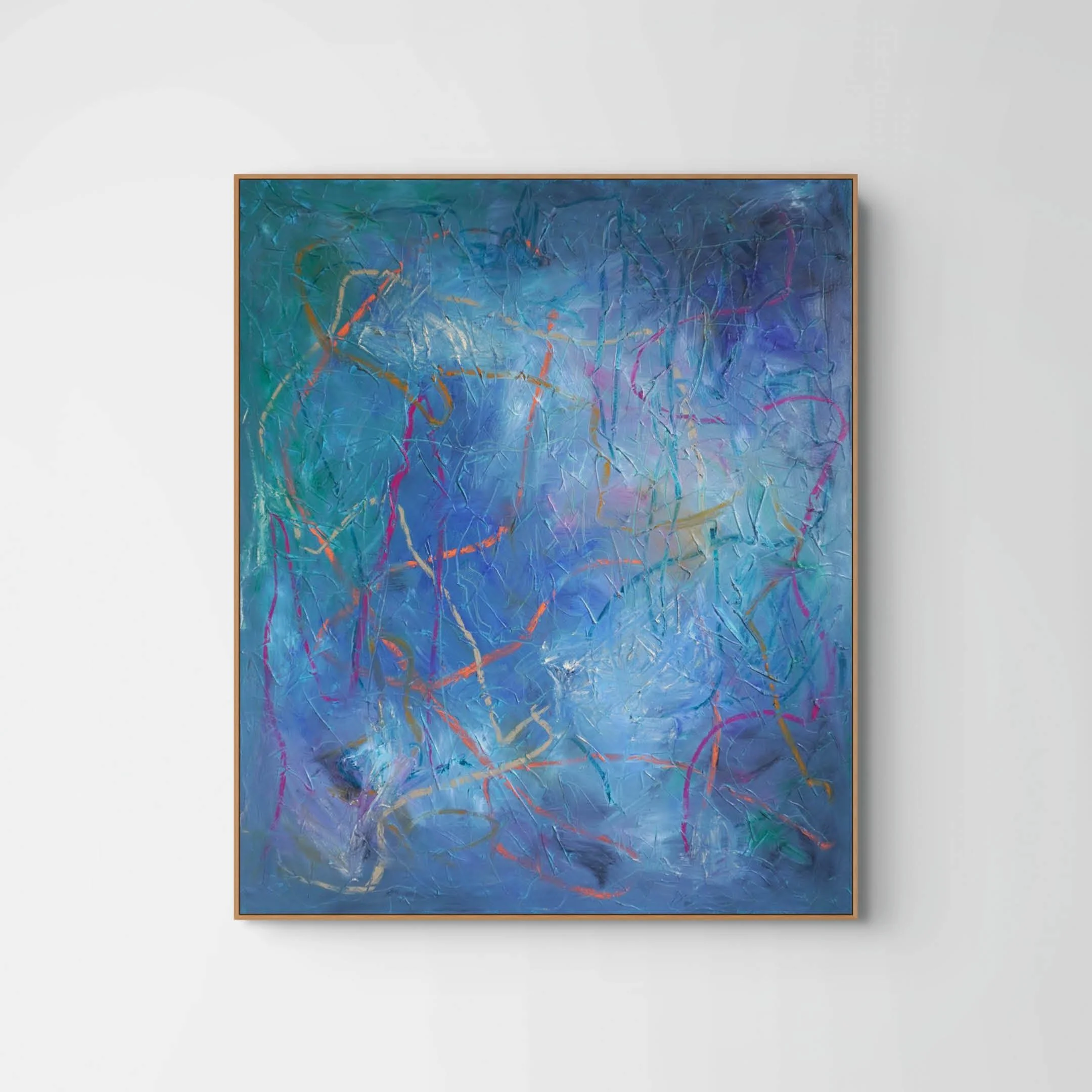 An abstract painting with a mix of blue, purple, orange, and pink streaks and shapes, framed in wood, hanging on a plain white wall.