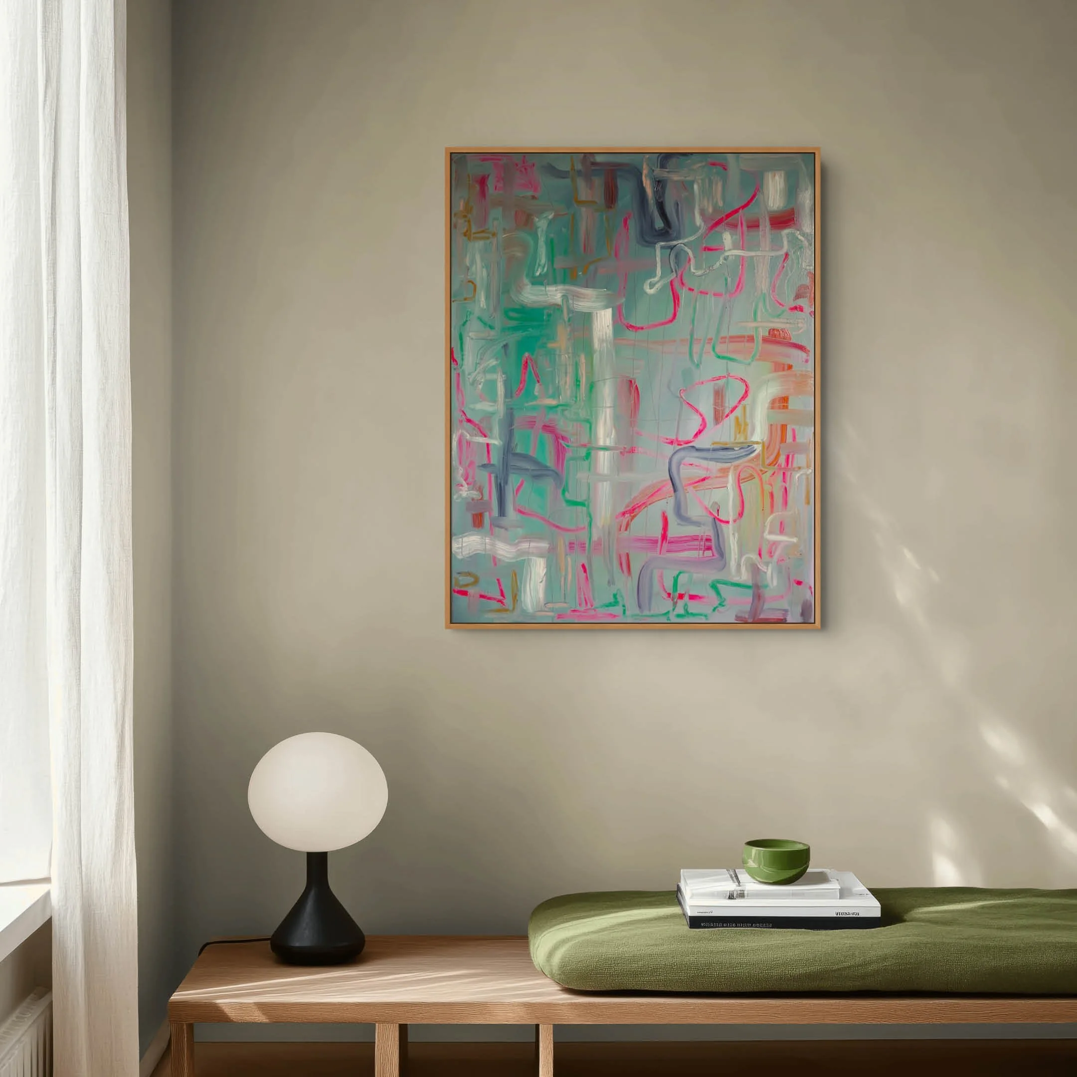 Living room corner with a black table lamp, abstract art on the wall, a white side table with a stack of books and a green bowl, and a green cushioned ottoman.