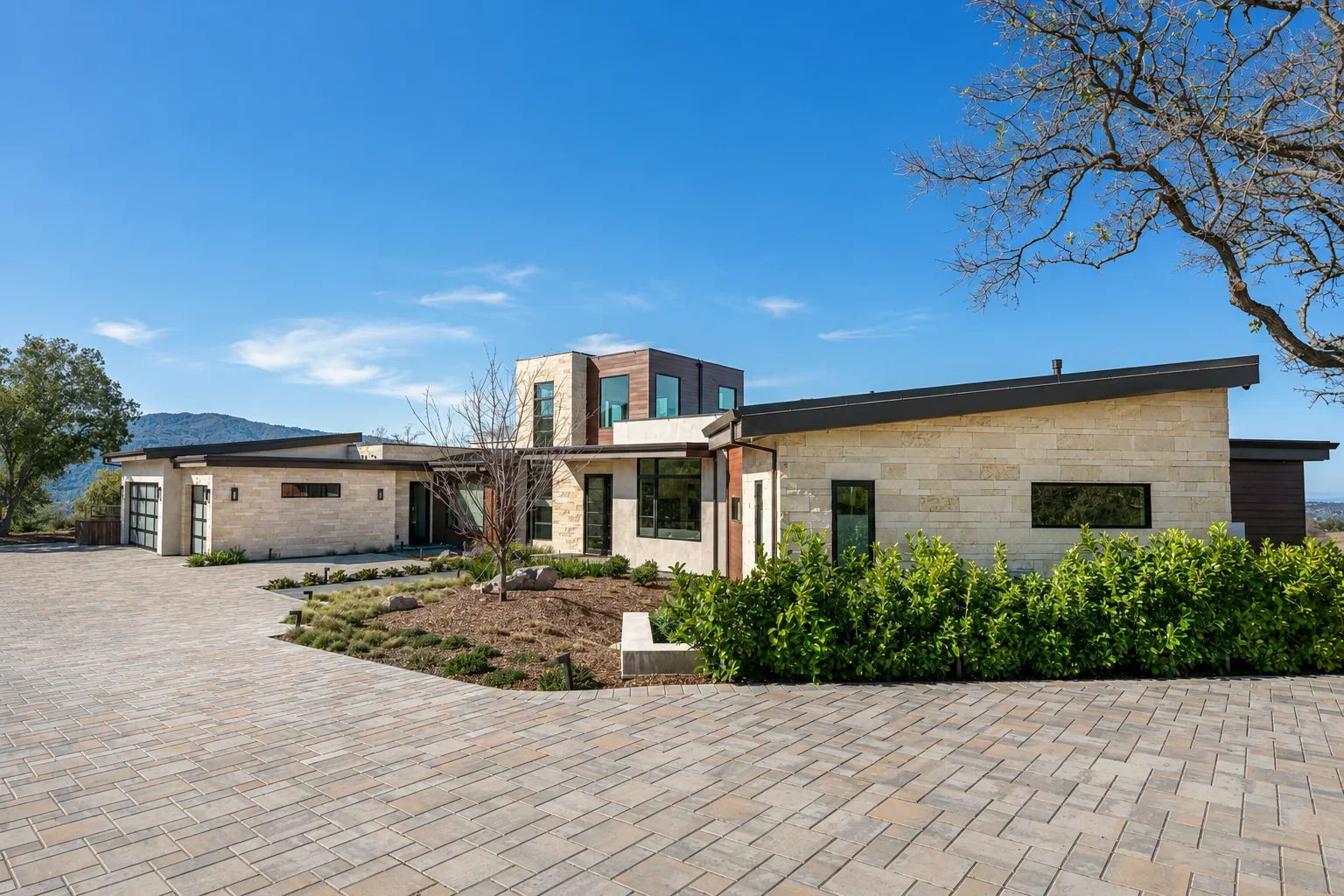 Front exterior of Gumtree in Los Gatos, featuring a stone-clad modern residence, expansive glazing, and a landscaped approach under an open sky.