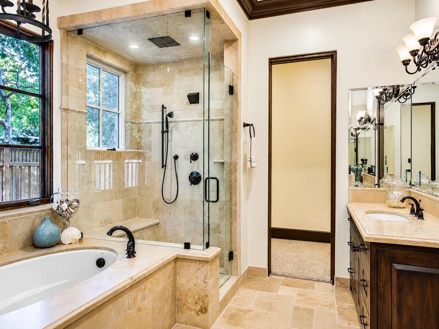 Bathroom at Villa Englewood in Los Gatos featuring a glass-enclosed shower, freestanding tub, wood vanity, decorative lighting, and views to the surrounding greenery.