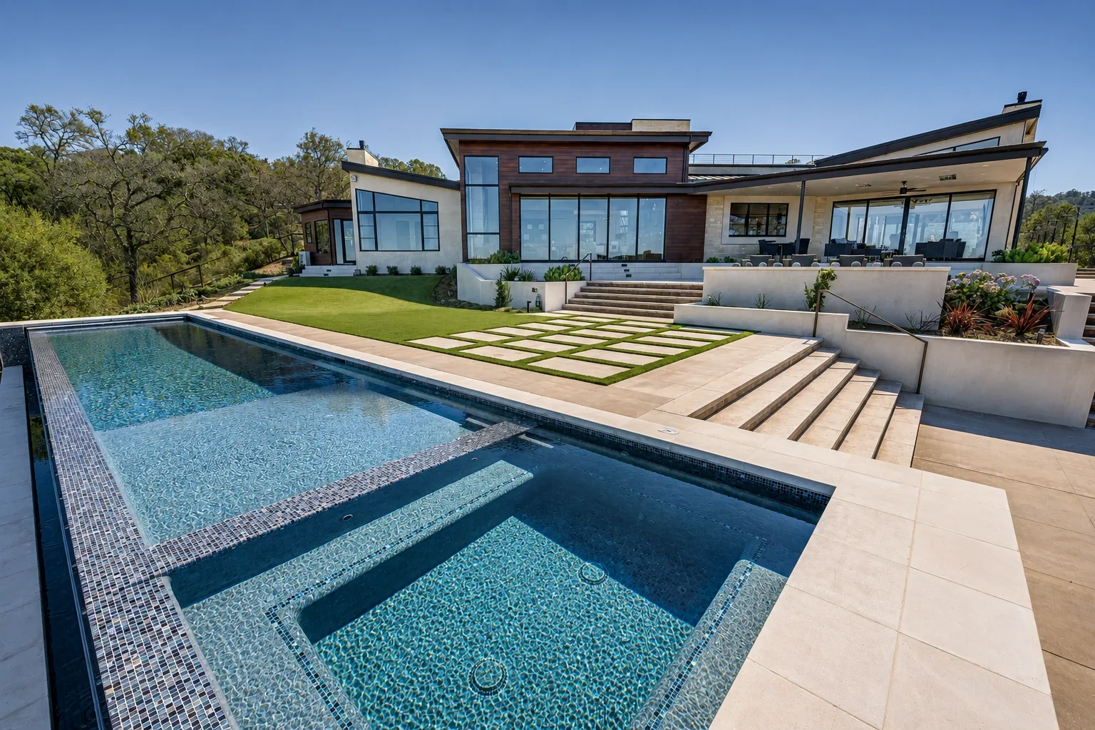Rear outdoor living area at Gumtree in Los Gatos, featuring expansive glass walls, a landscaped lawn, outdoor seating, a swimming pool, and an integrated spa.