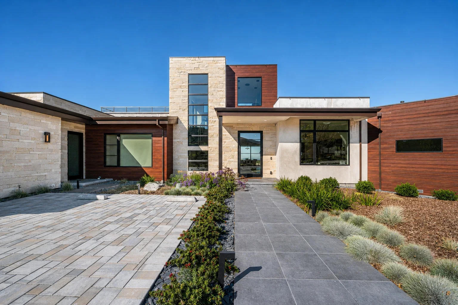 Exterior of Gumtree in Los Gatos, featuring a modern residence with stone and wood cladding, a paved approach, and layered landscaping beneath a clear sky.