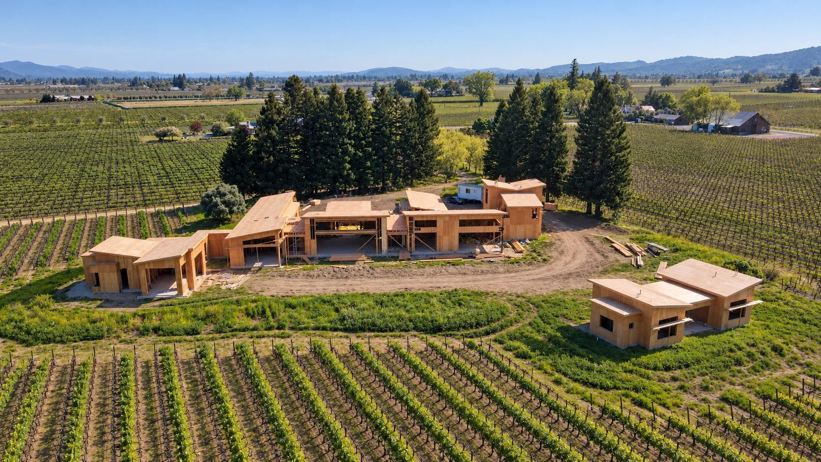 Aerial view of a Massei Construction residential development project underway in a vineyard setting, with active construction surrounded by trees and rolling hills.