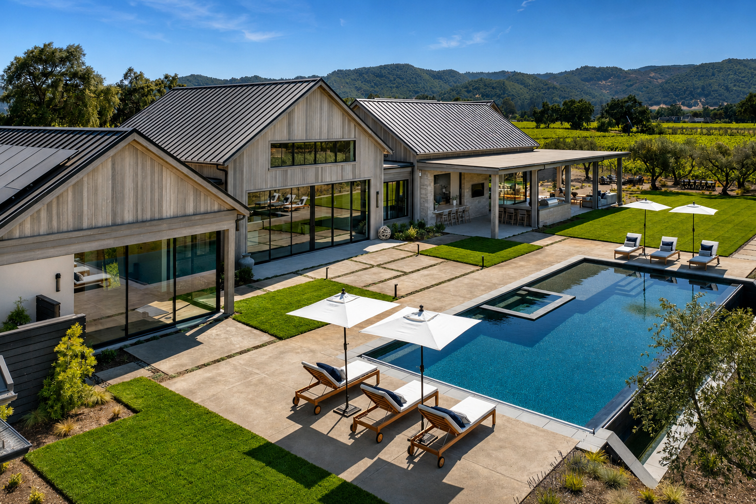 Pool terrace at Trubody Ranch in Napa Valley featuring a contemporary residence, swimming pool, sun loungers, outdoor seating, landscaped grounds, and mountain views.