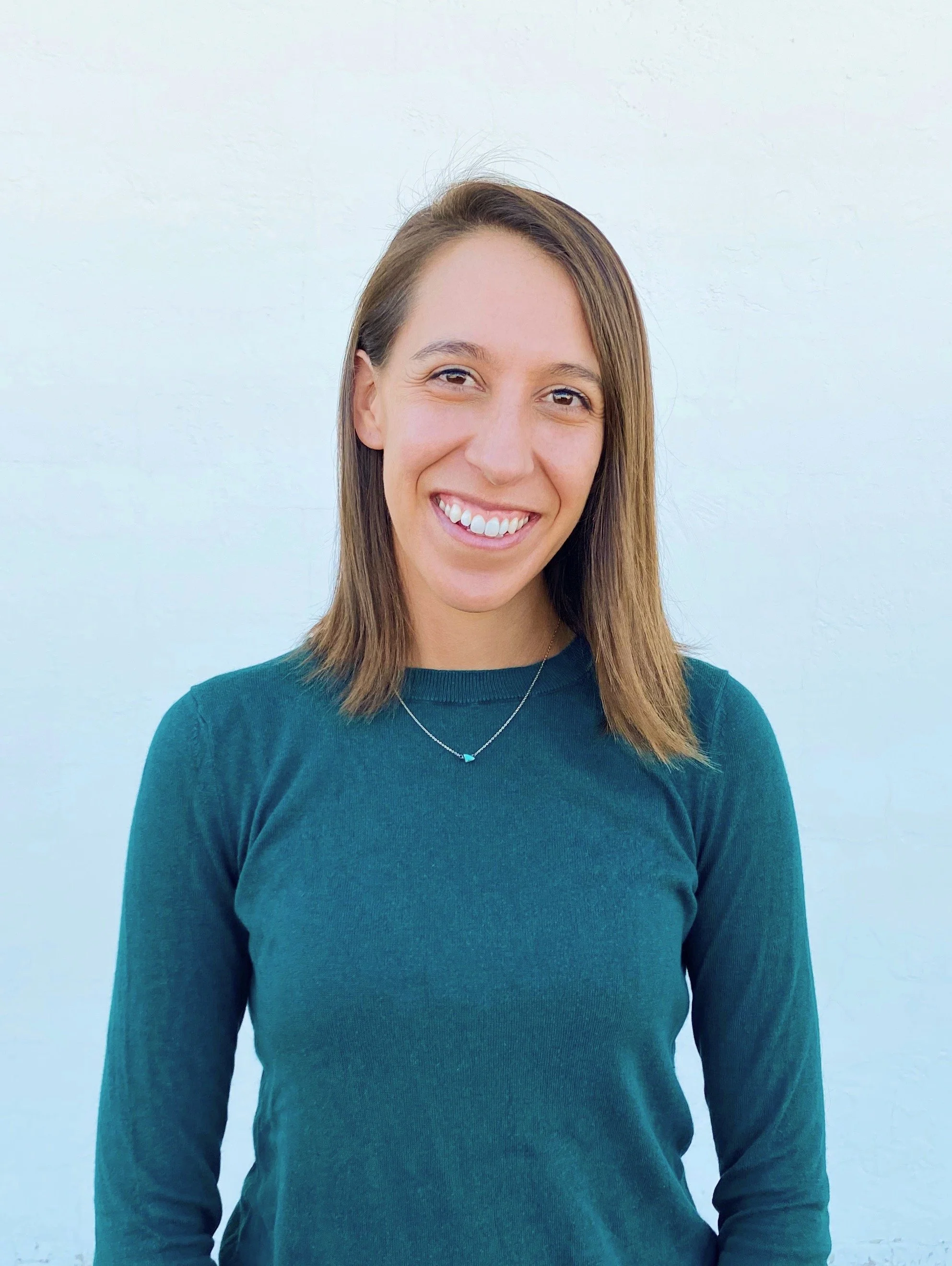 A headshot of Patty Murray, couples therapist and somatic therapist in Denver. She has shoulder-length brown hair, a warm smile, and is standing against a white wall.