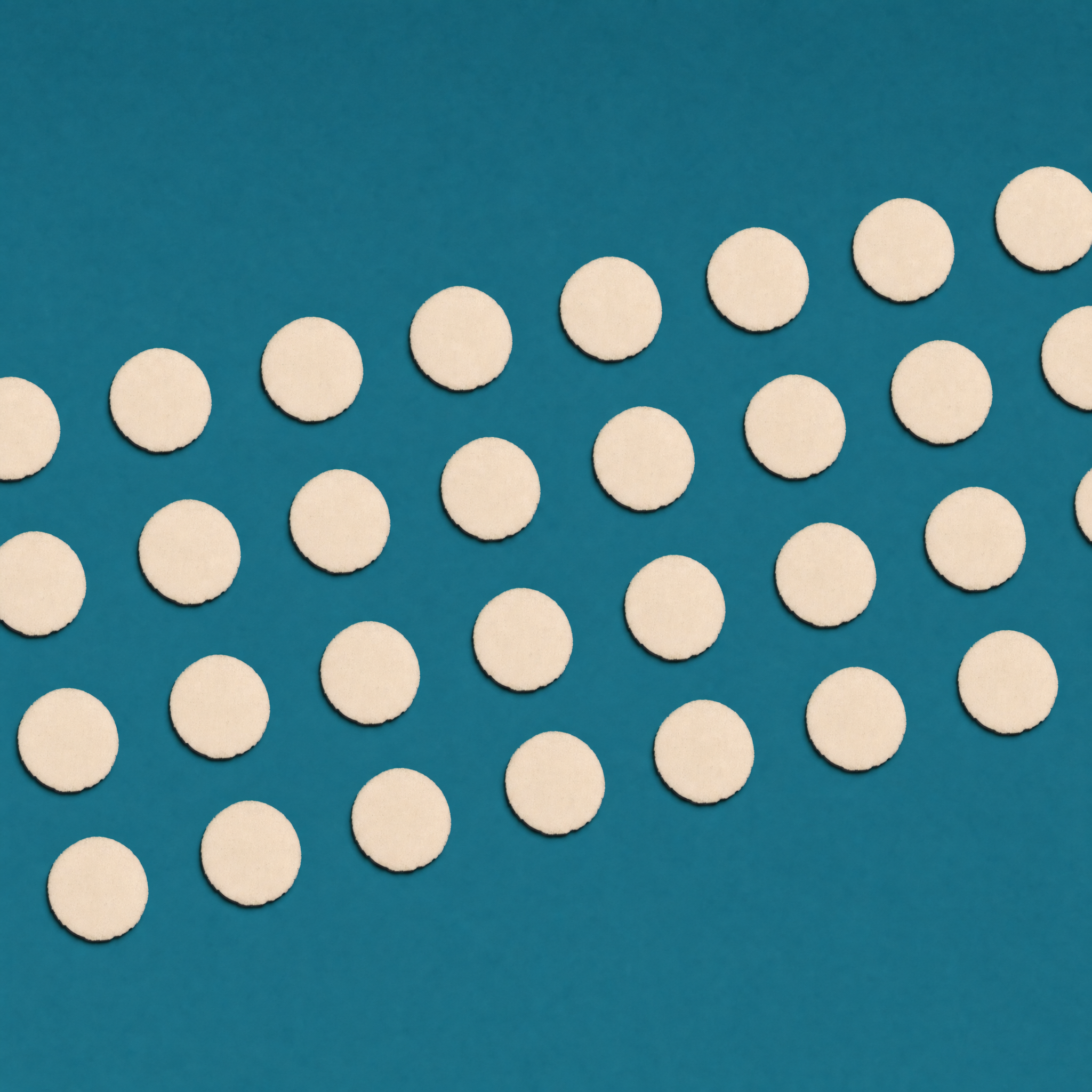 Multiple white circular Willie's Melts tablets arranged in rows on a blue background.