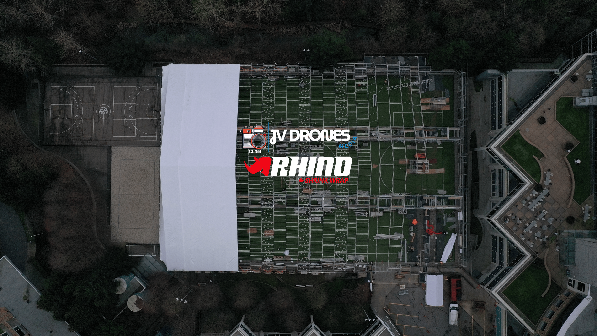 Top-down aerial drone view of scaffold and white shrink wrap containment on a commercial project in British Columbia