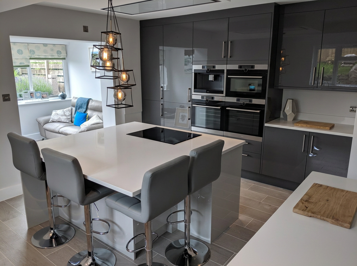 Modern kitchen with a white island, gray cabinets, built-in appliances, and a seating area with a sofa in the background.