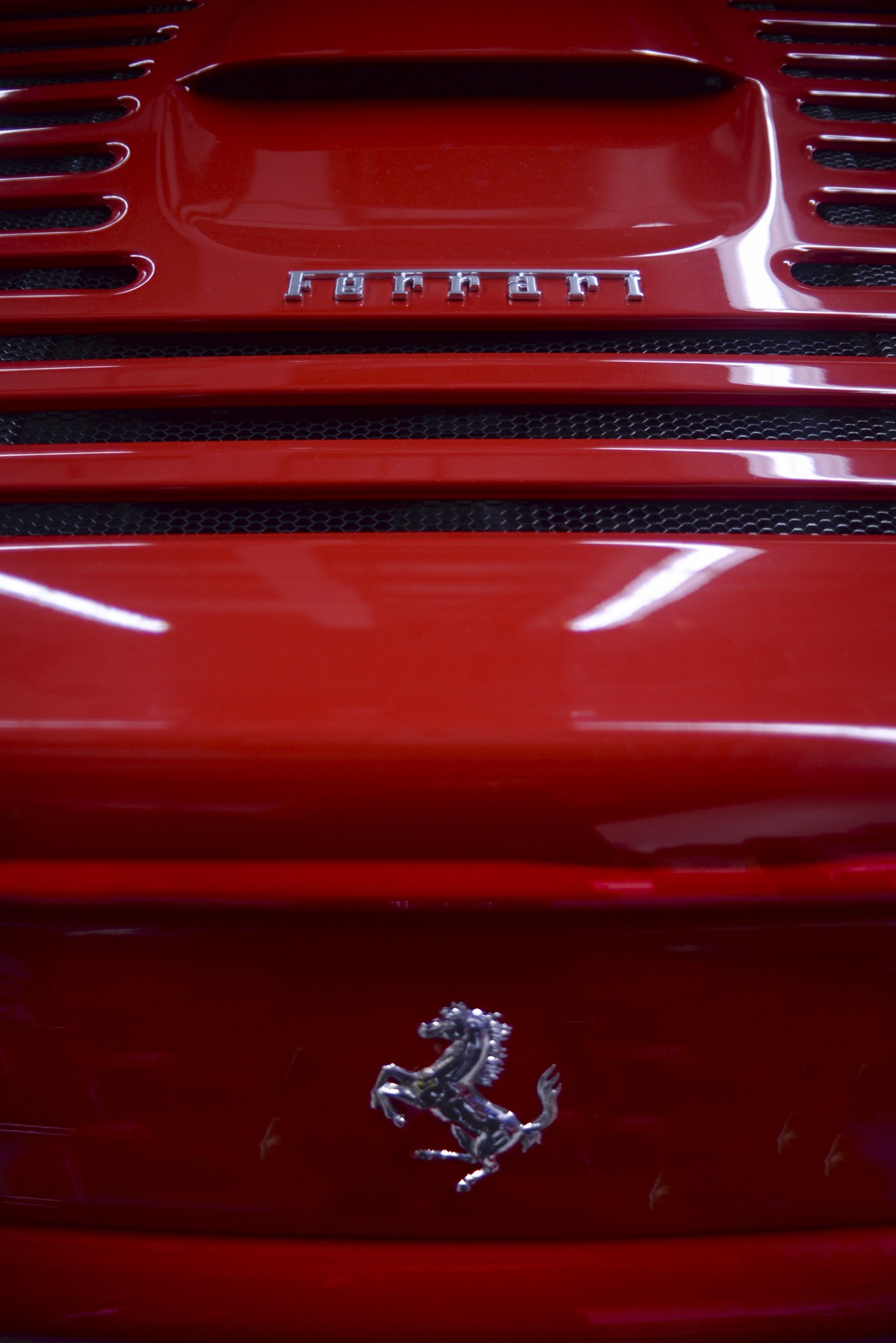 Close-up of a red Ferrari car grille with the Ferrari logo and a prancing horse emblem.