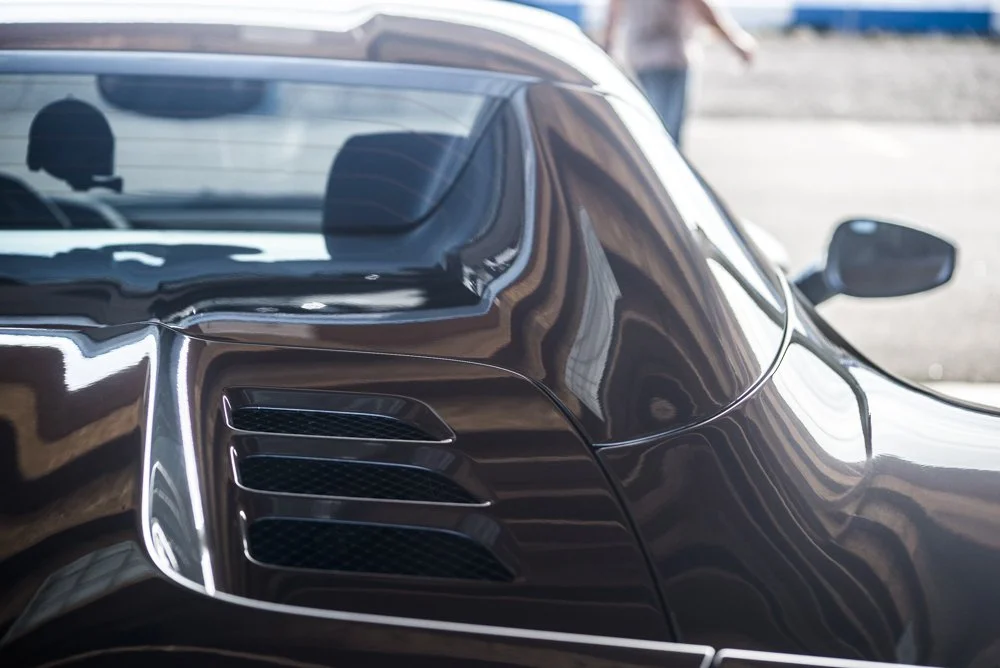 Close-up of a black sports car with sleek lines and vents on the side.