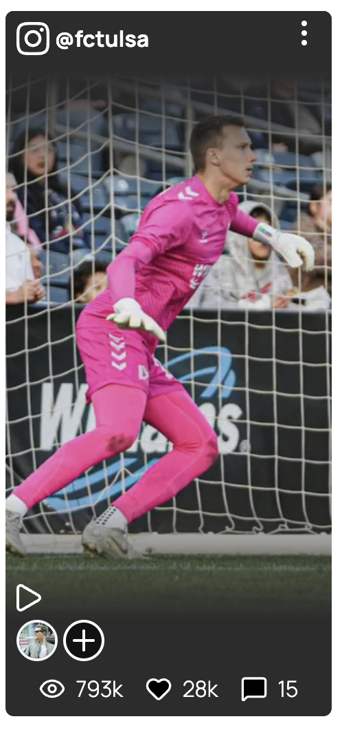 A soccer goalkeeper wearing a bright pink uniform and gloves, standing near the goal, with spectators in the background.