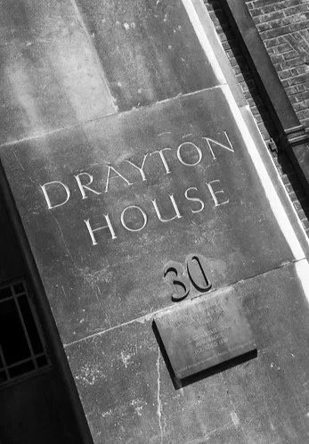 Close-up of a building corner with the words 'DRAYTON HOUSE' and the number '30' engraved on the wall.