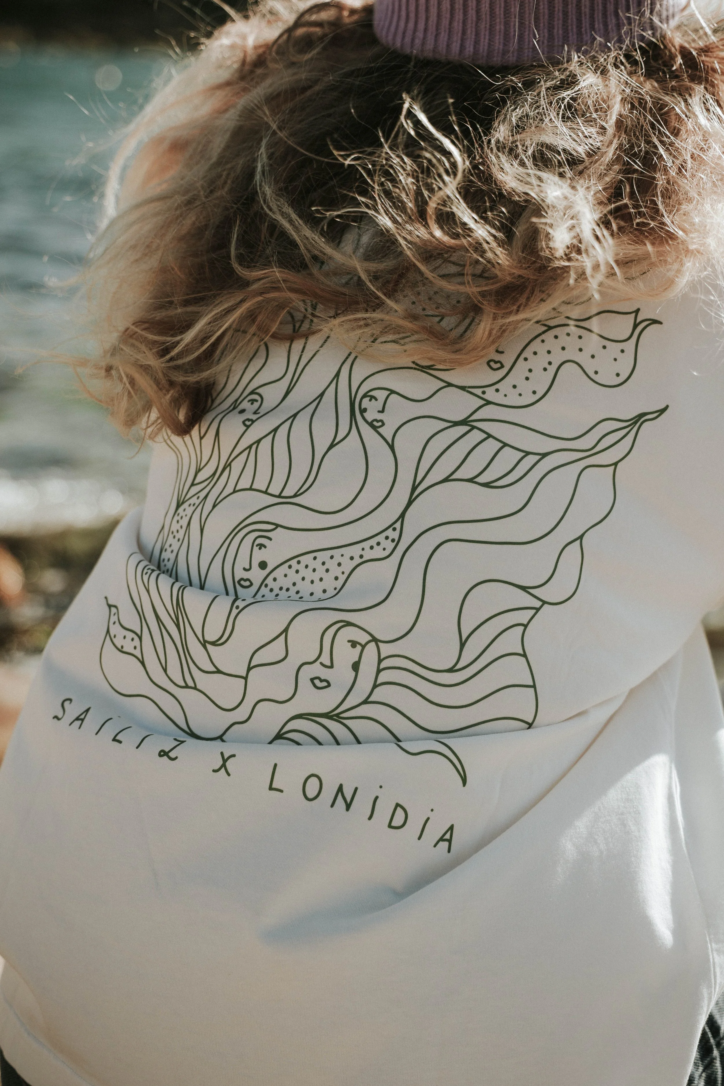 Un sac en tissu blanc avec un dessin linéaire noir représentant des visages et des formes abstraites, avec le texte 'SAILIZ LONDIA de visible, pour les femmes navigatrices