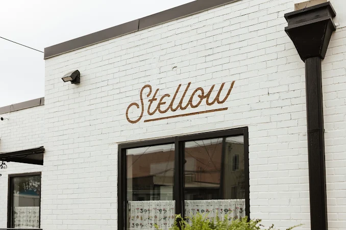 Exterior of a white brick building with the word 'Stellow' written in cursive above a window.