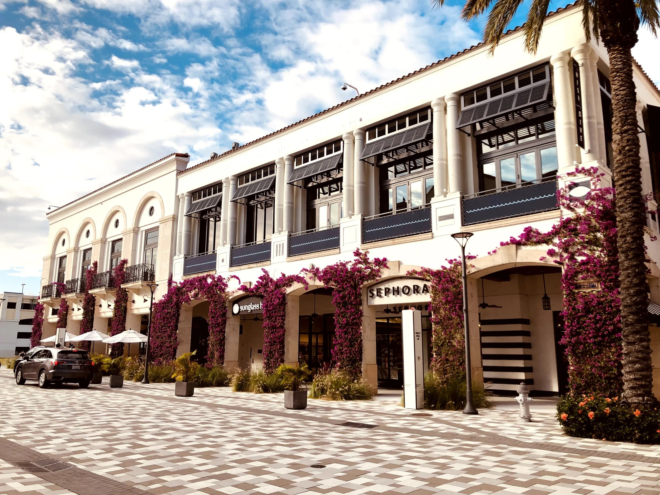 The Square in West Palm Beach with white architecture, palm trees, and bougainvillea.