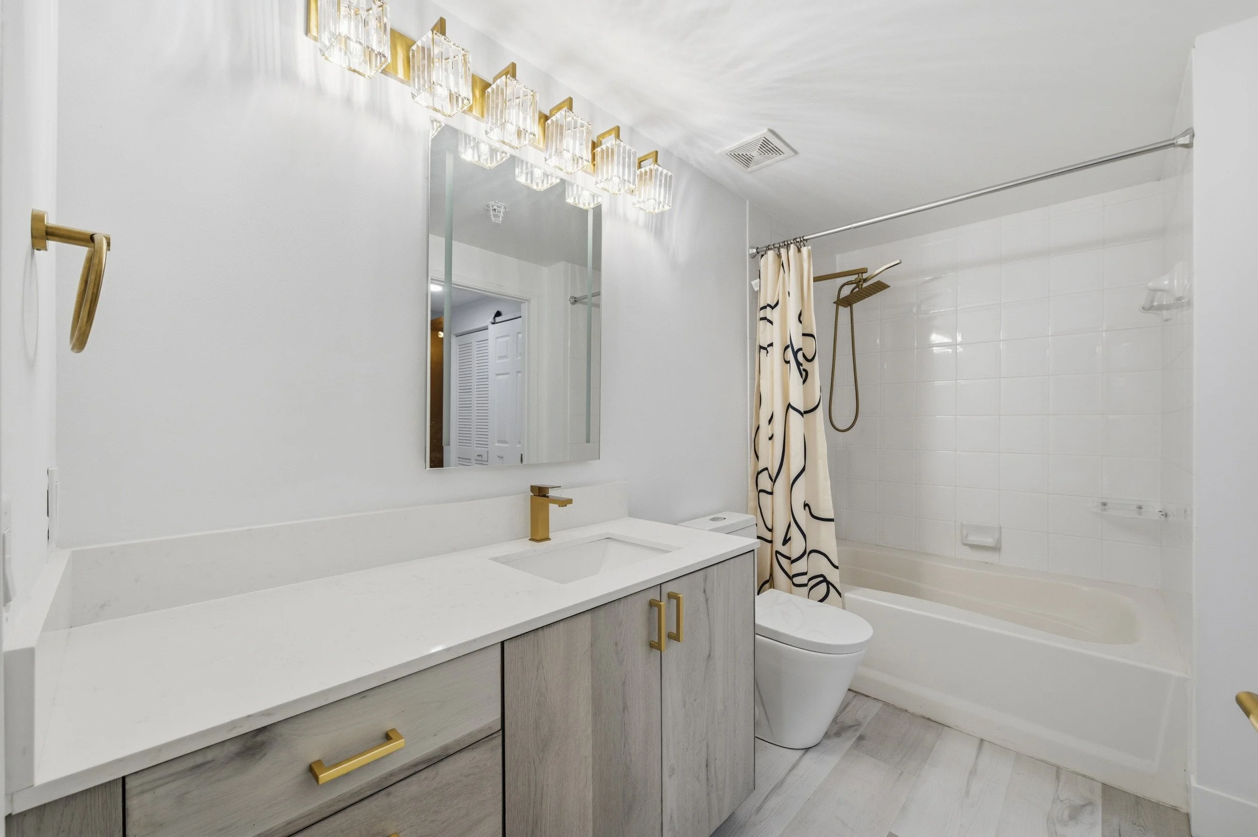 White bathroom with gold fixtures and a tub-shower combination.