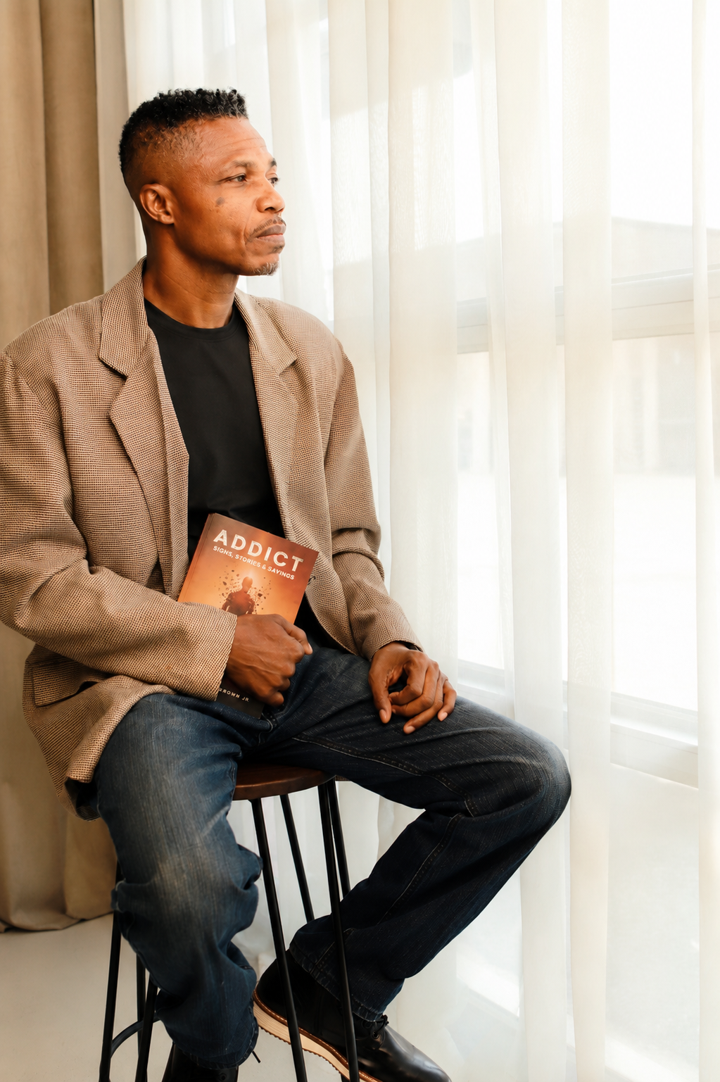 Author A. Mustafa Tut Brown Jr. seated with his book ADDICT.