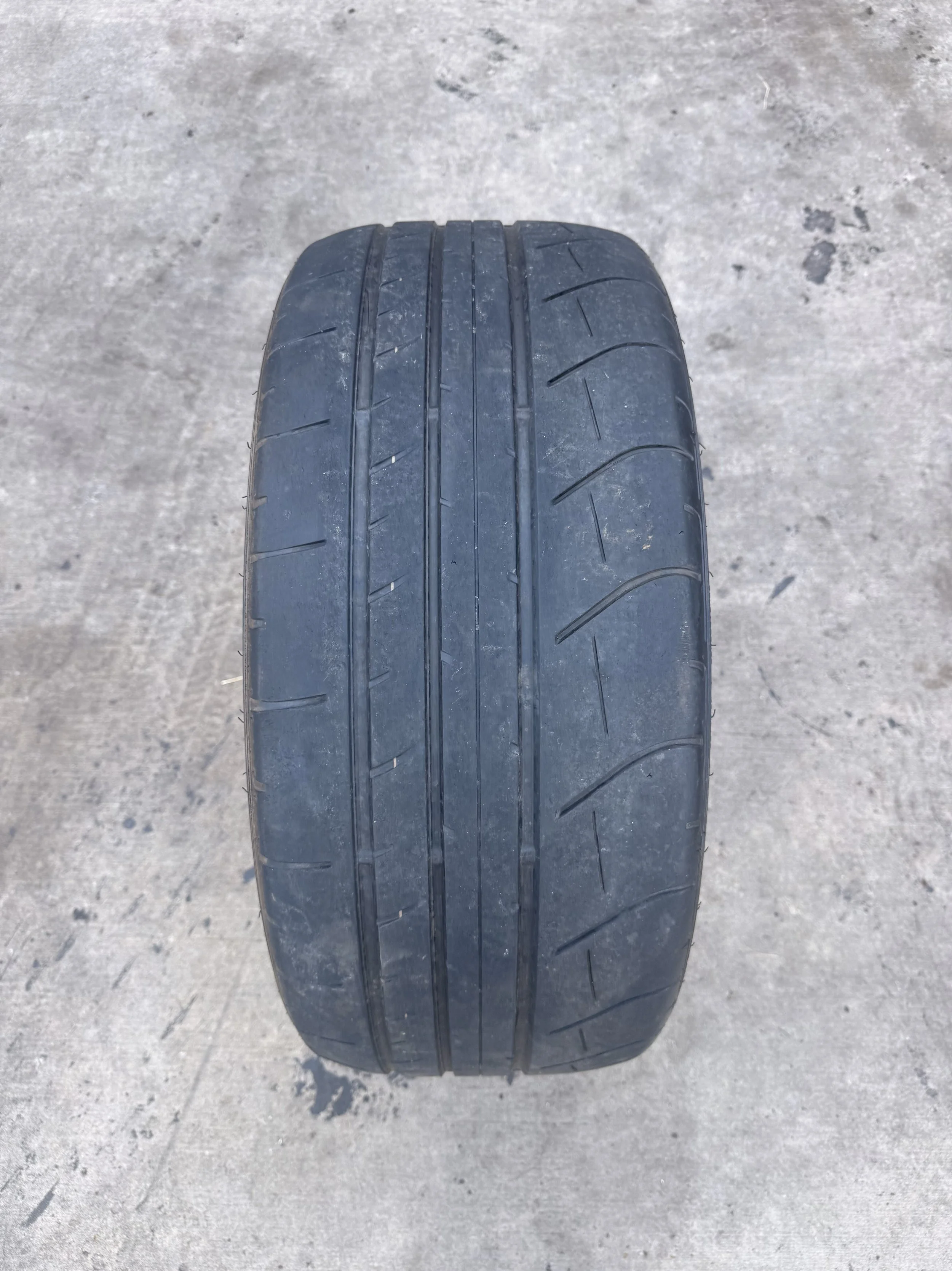 A close-up of a black car tire on a concrete surface.