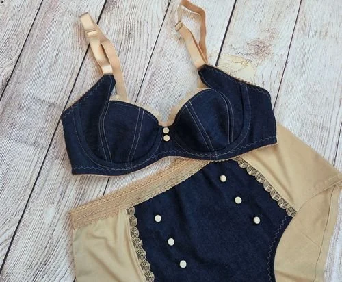 A beige and navy lingerie set with a bra and matching panties on a light wooden surface.