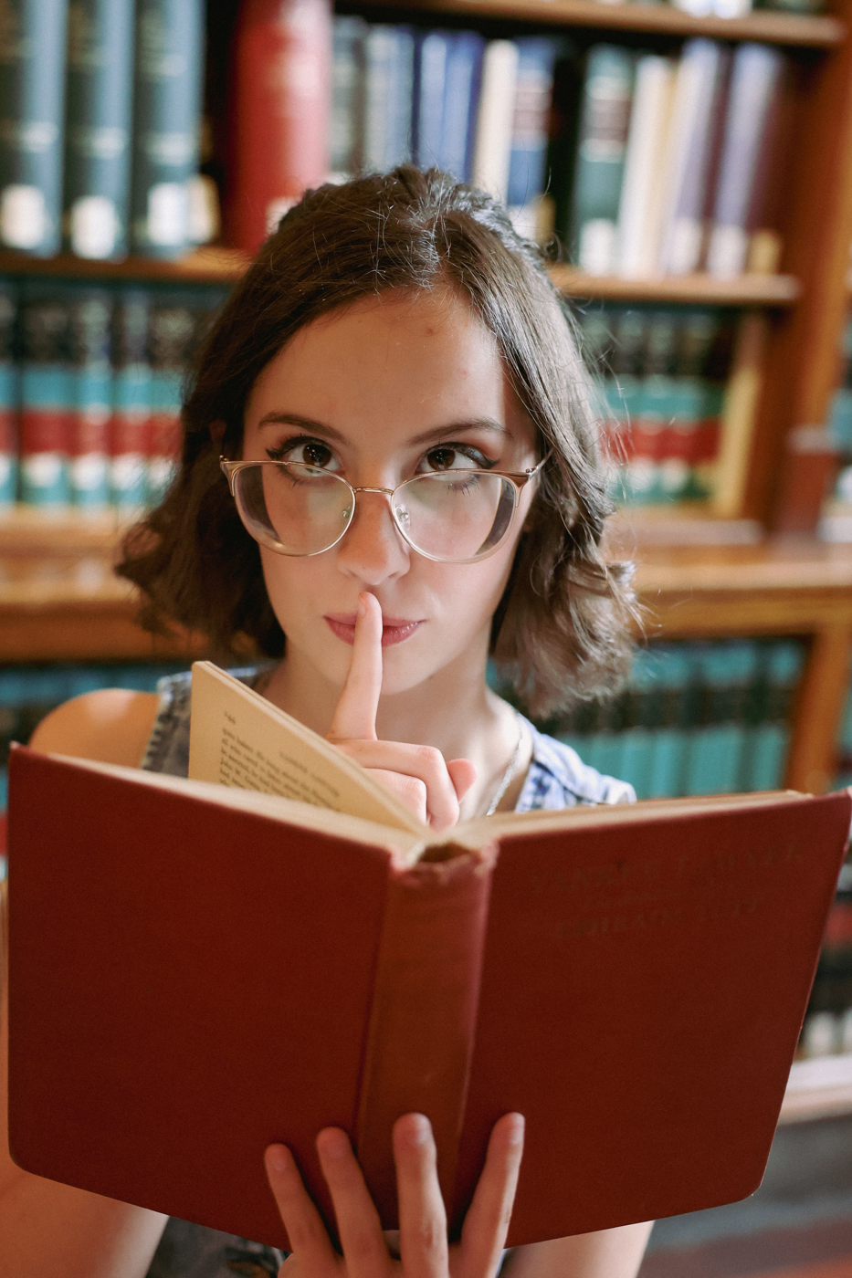 Senior portrait holding a book in a library.