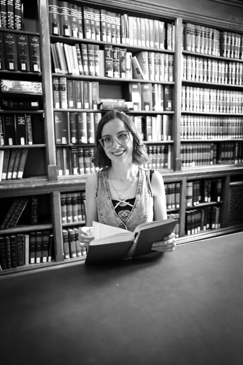 Black-and-white senior portrait at a library table.