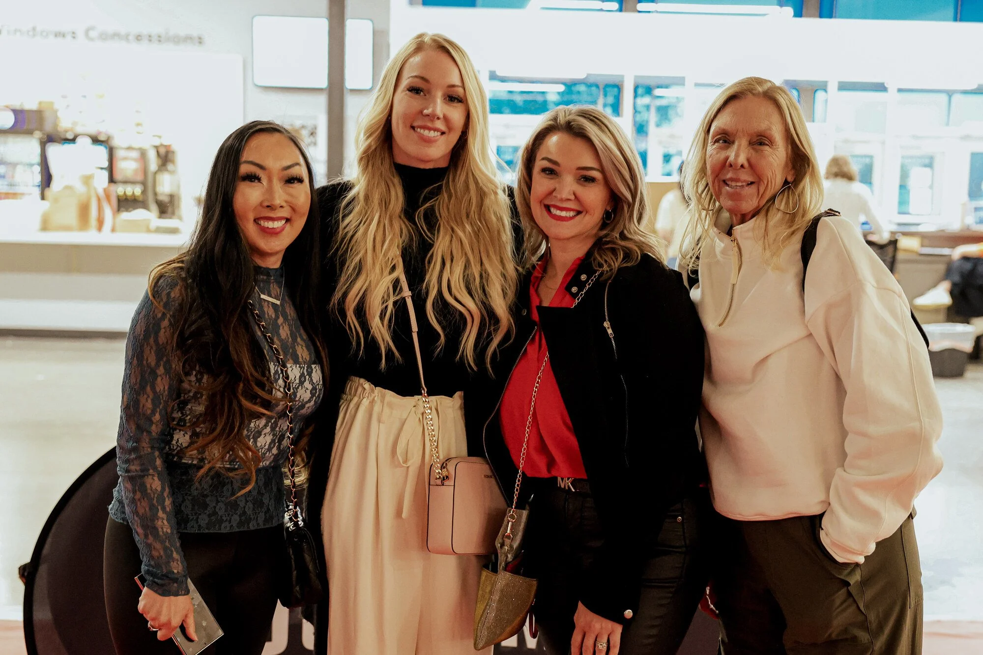 Four women posing and smiling together at the concession windows during the gala.