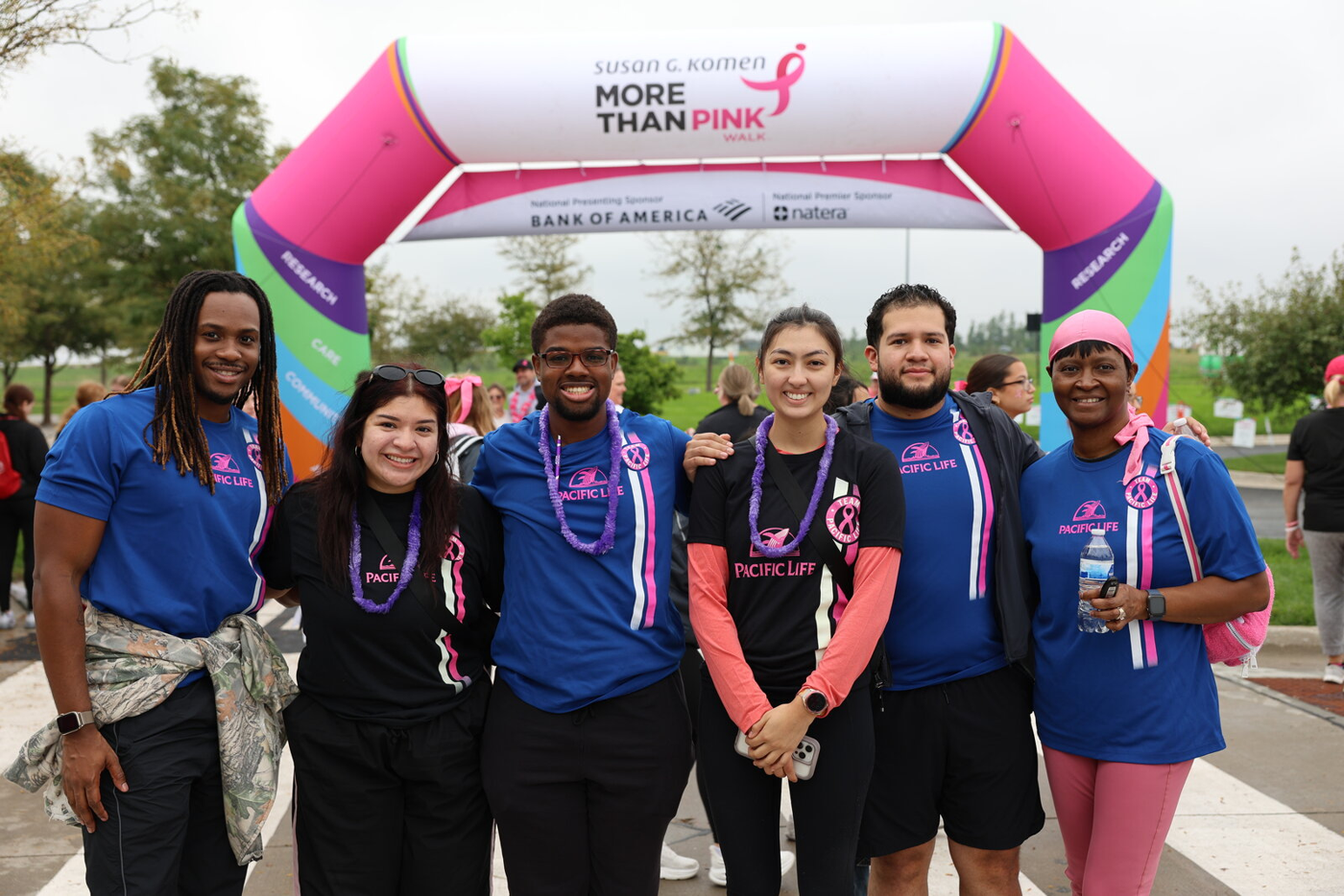 Walk participants gathered beneath a pink event entrance arch.