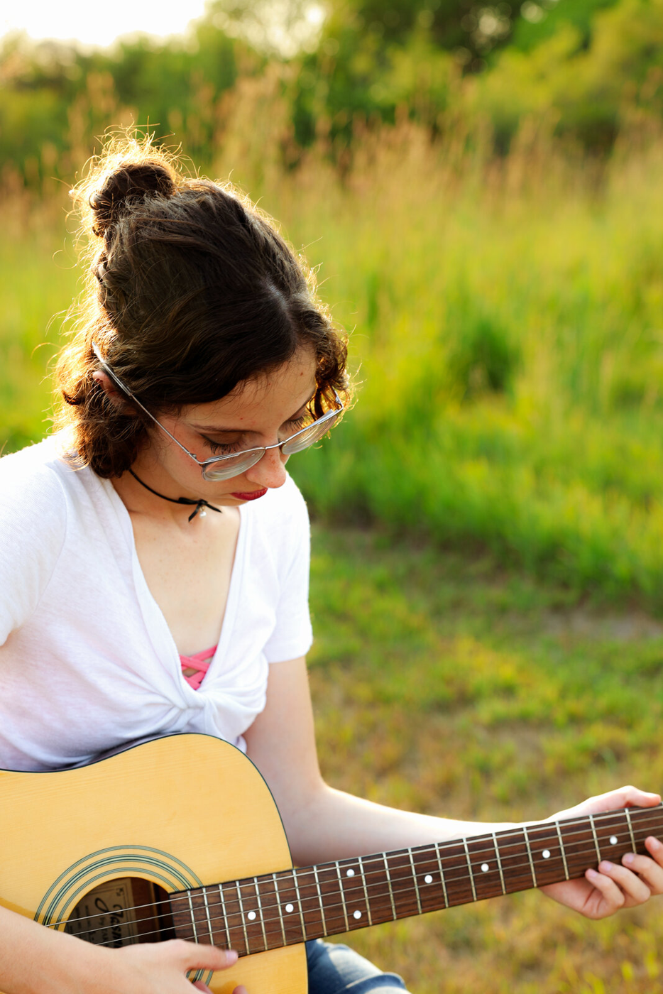 Senior portrait holding a guitar outdoors.