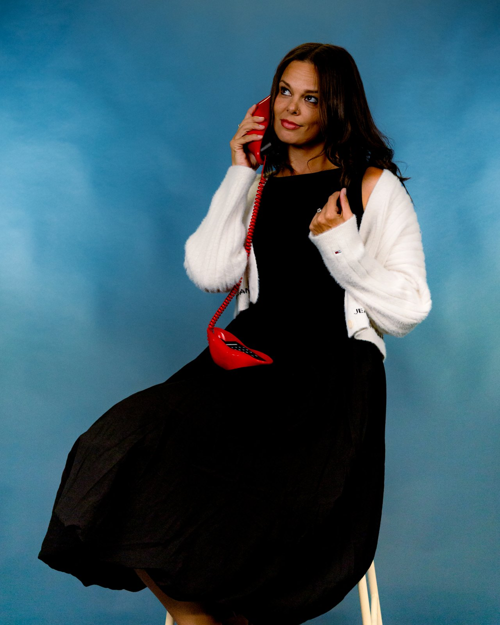 Mikayla holding a red telephone against a blue backdrop.