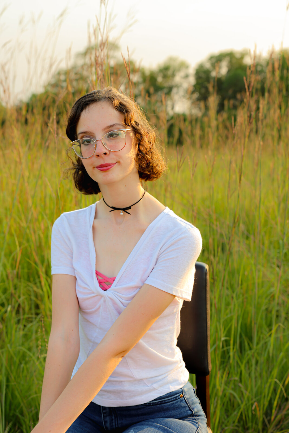 Senior portrait in tall grass at golden hour.