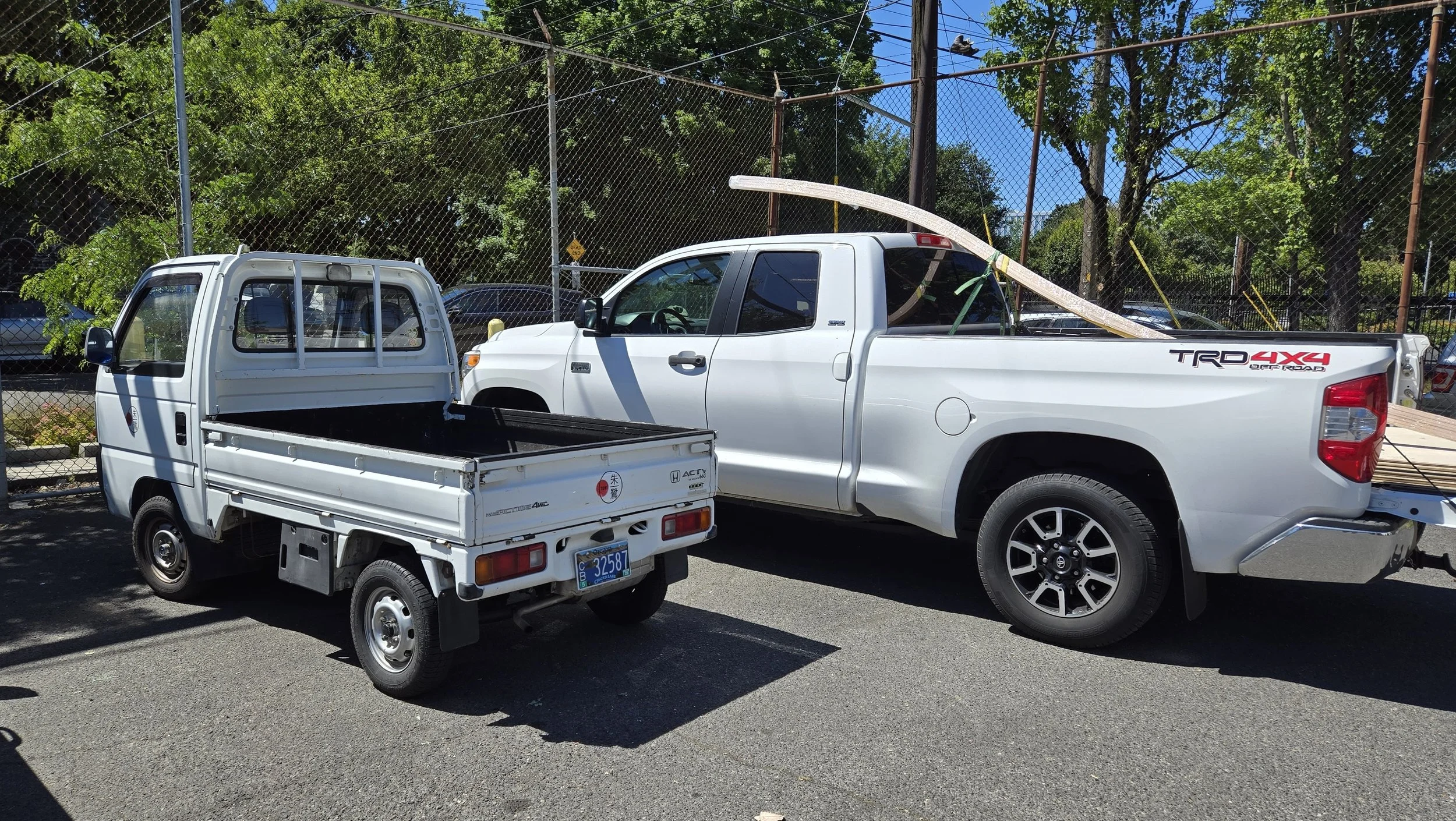 A 1994 Honda Acty kei truck parked next to a full sized pickup.