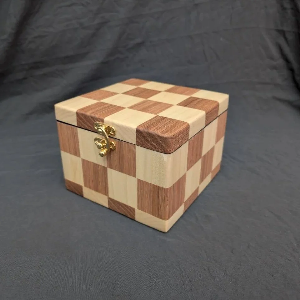 A wooden chessboard-shaped jewelry box with a clasp, made of different colored wood squares.